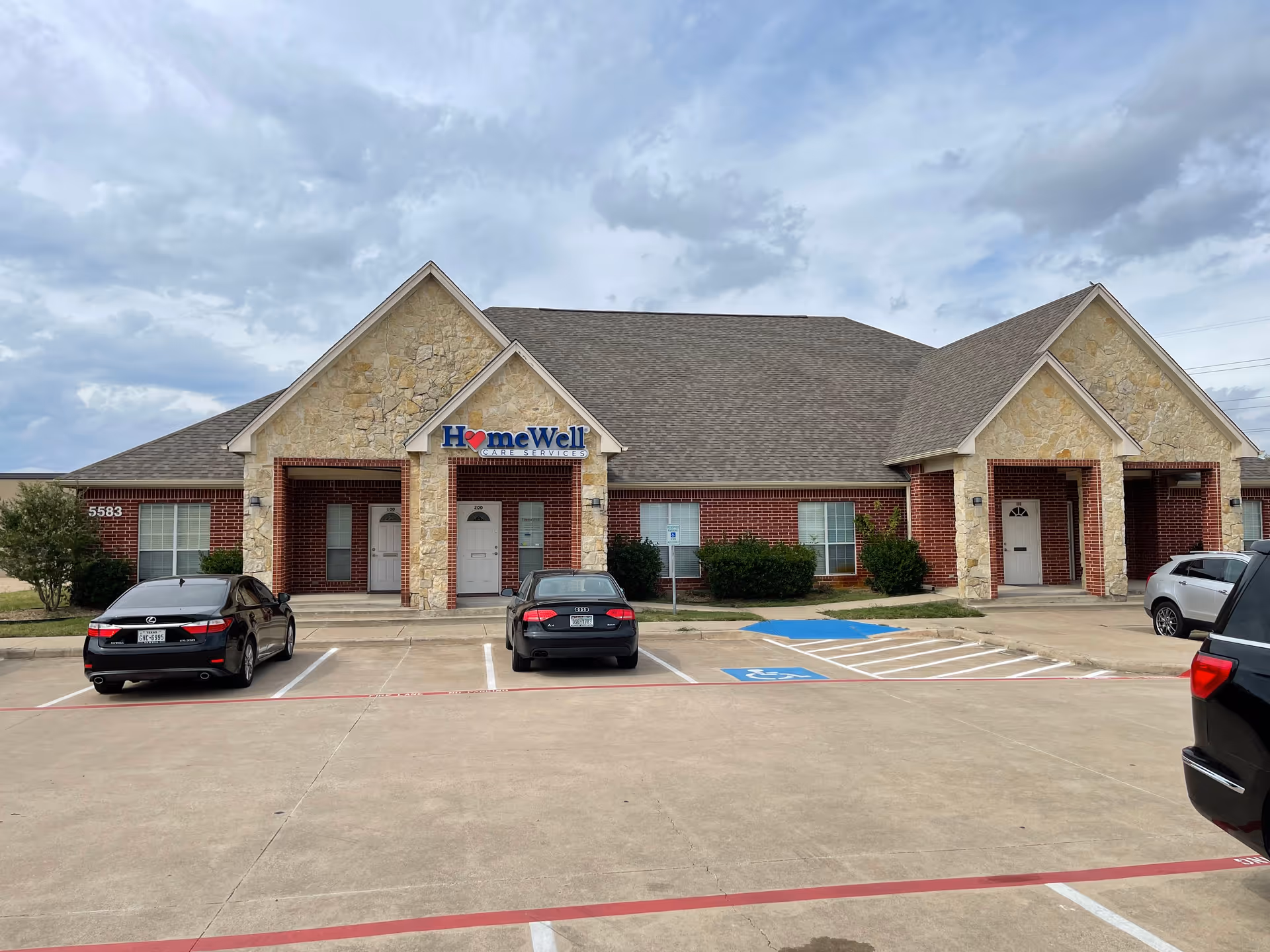 Senior living facility HomeWell with stone facade and parked cars in a lot.