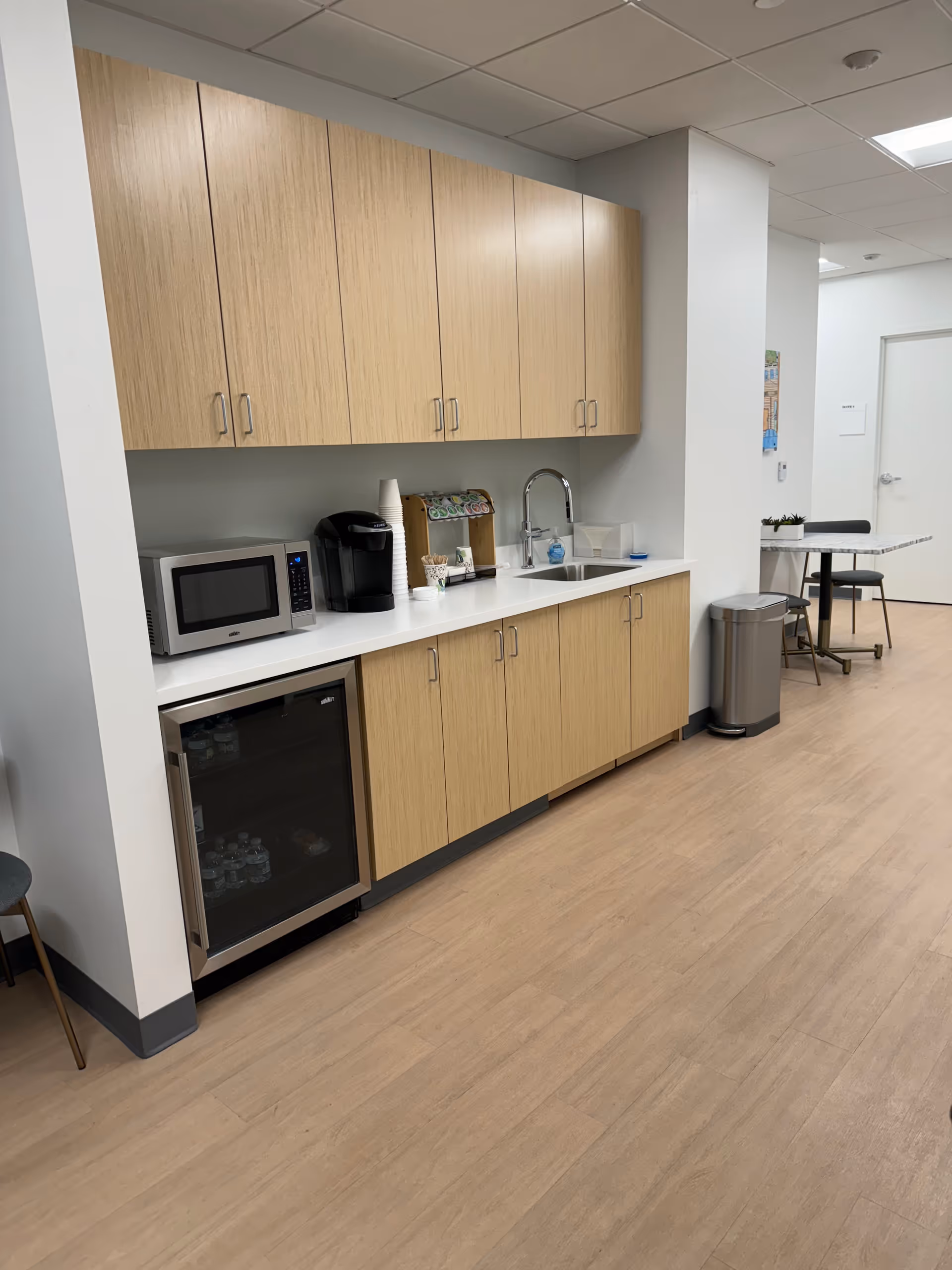 Interior kitchenette with wooden cabinets, sink, microwave, coffee maker, and mini-fridge.