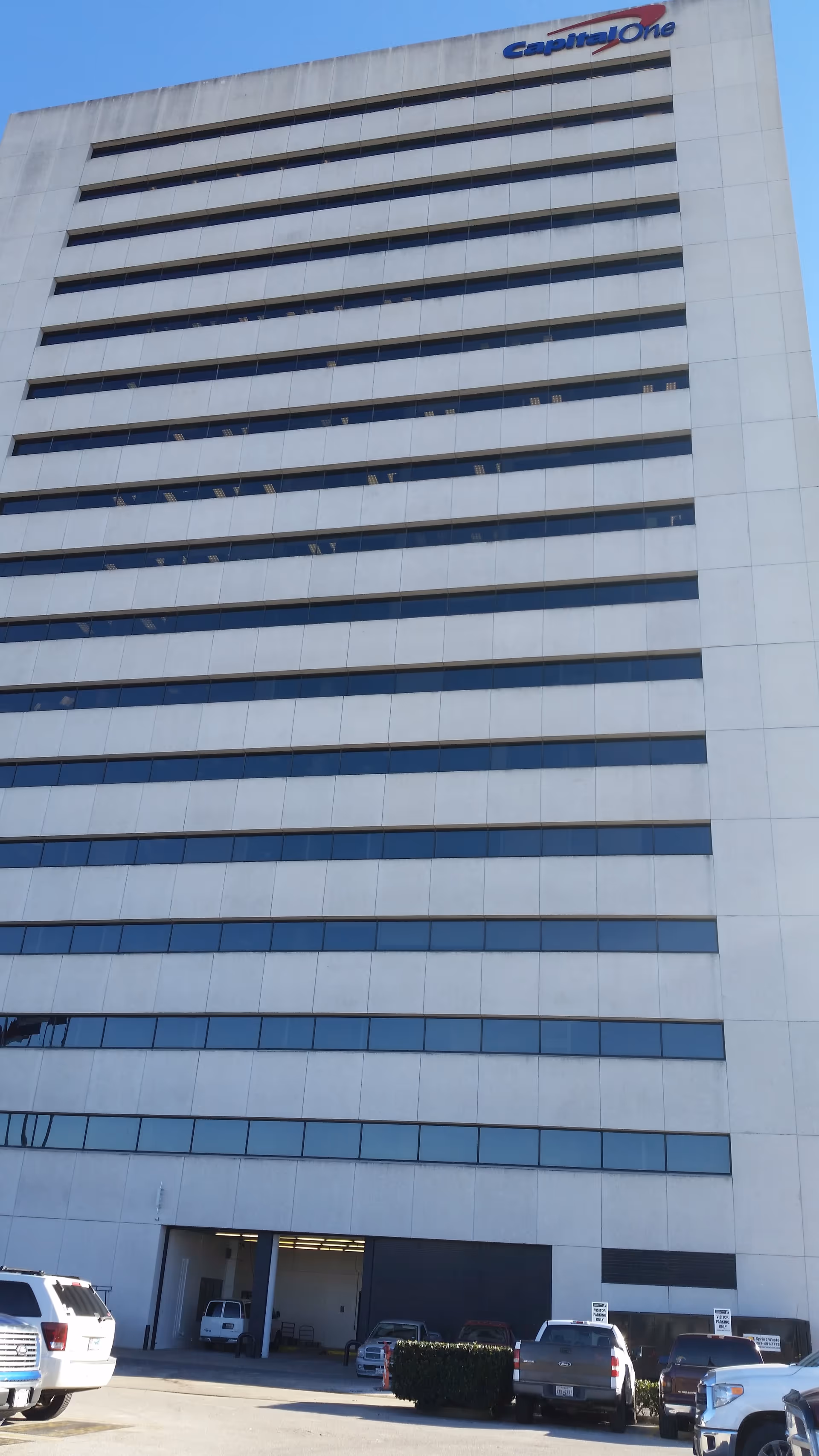 Tall white high-rise building with many windows and a Capital One sign at top.