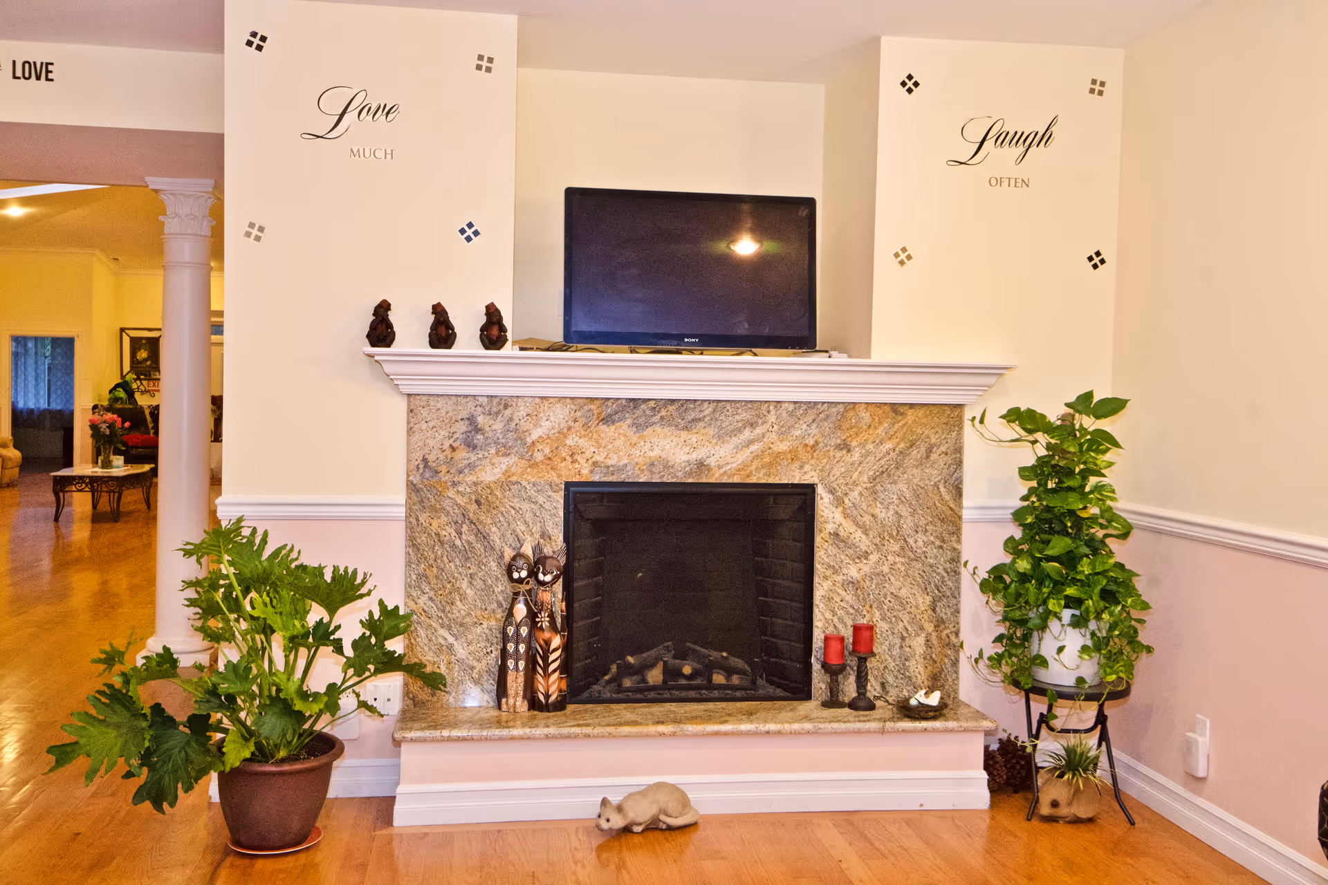 Cozy living room with a stone fireplace, TV above mantel, and potted plants.