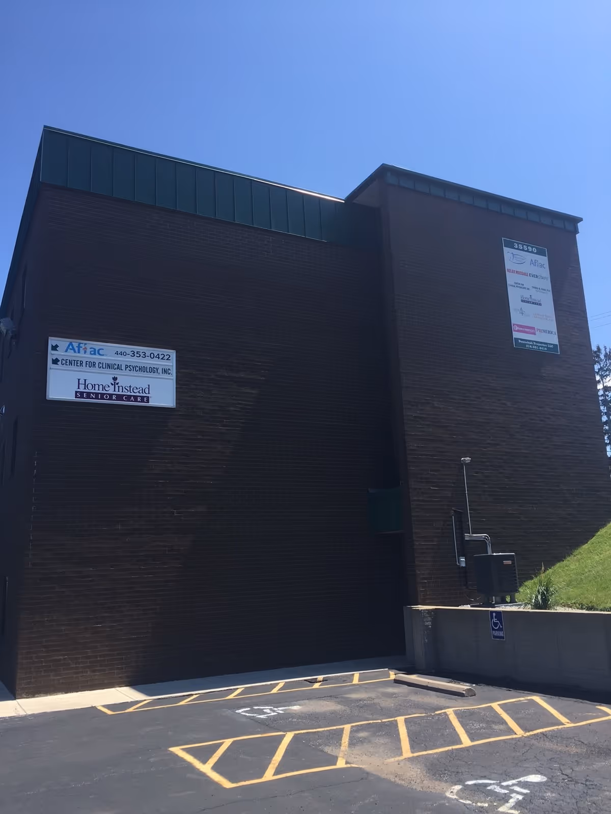 Brick exterior of a building with a Home Instead Senior Care sign and parking lot.