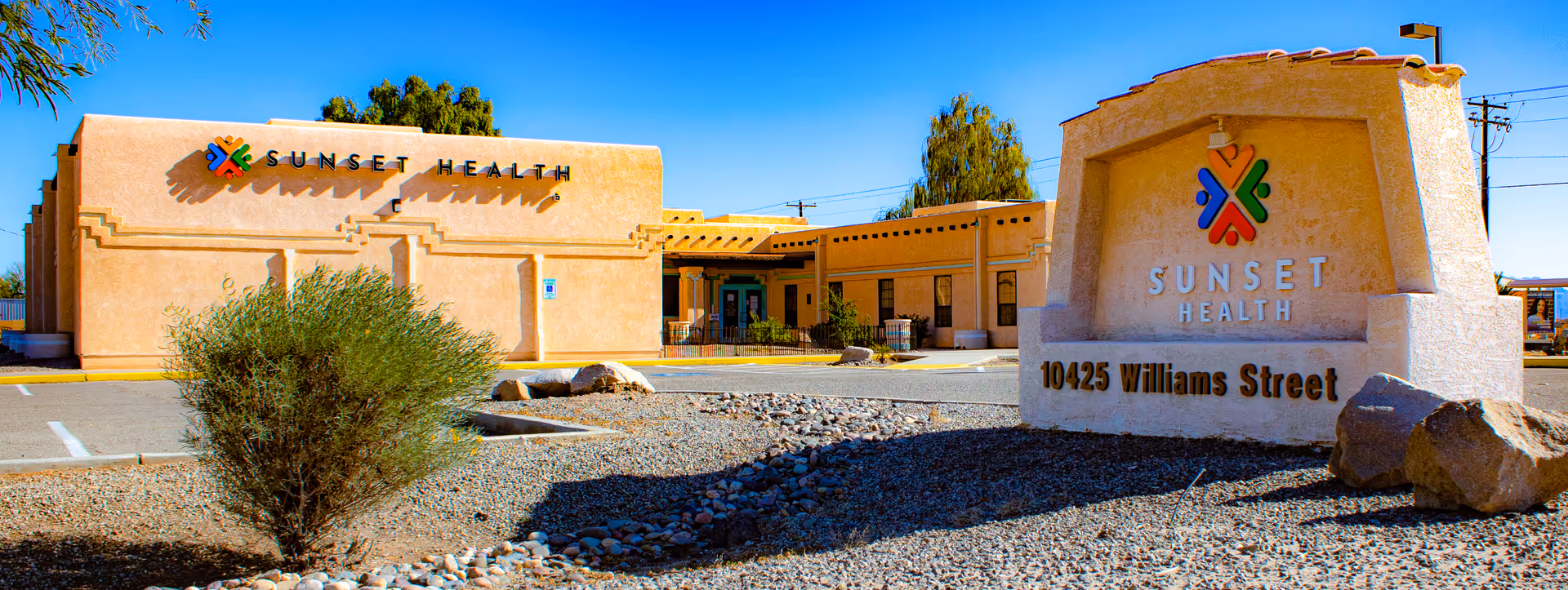 Sunset Health building exterior with a large stone sign and desert landscaping