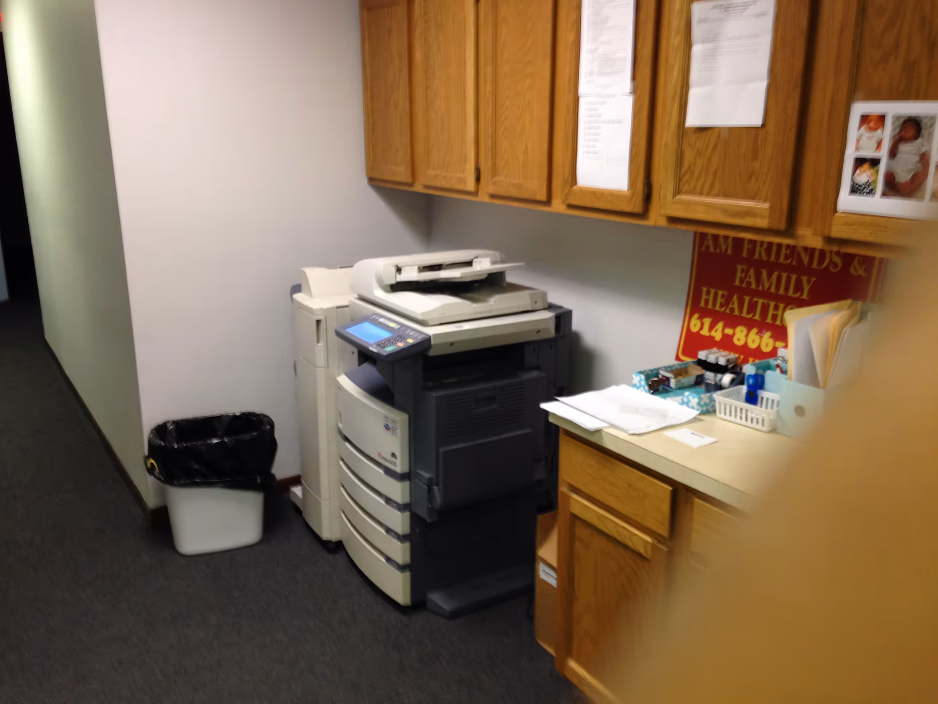 Office area with copier, printer, wooden cabinets, and a desk.