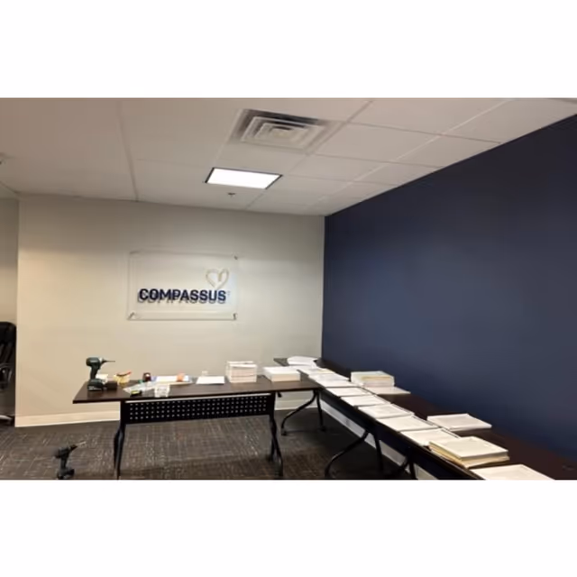 Office reception area with Compassus sign and tables covered in brochures.