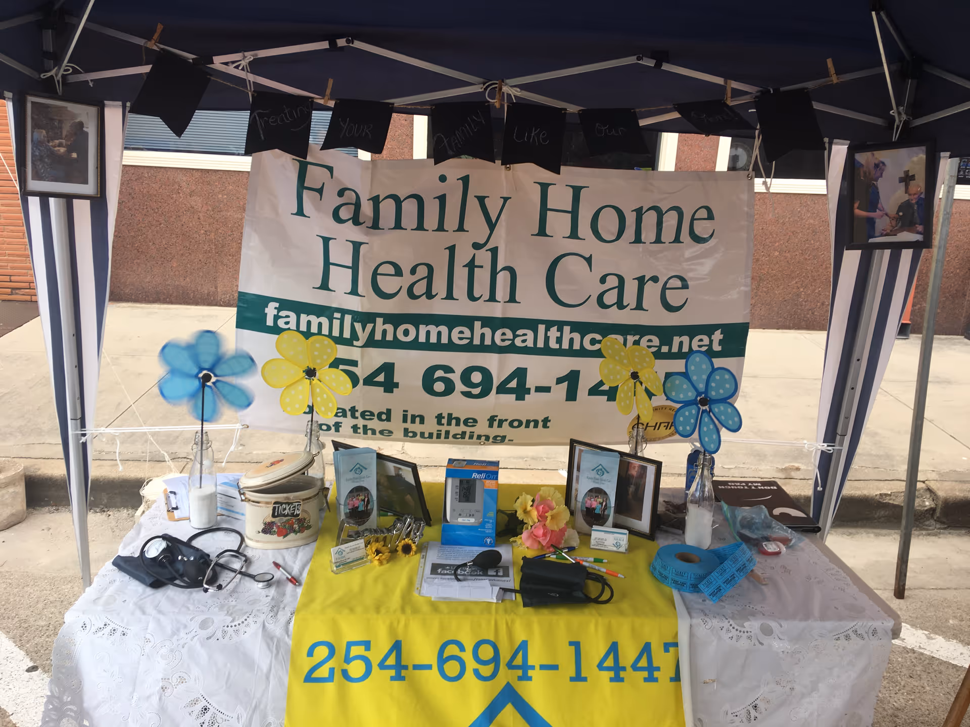 Outdoor booth banner reads 'Family Home Health Care' with tables, decor, photos, and medical items.