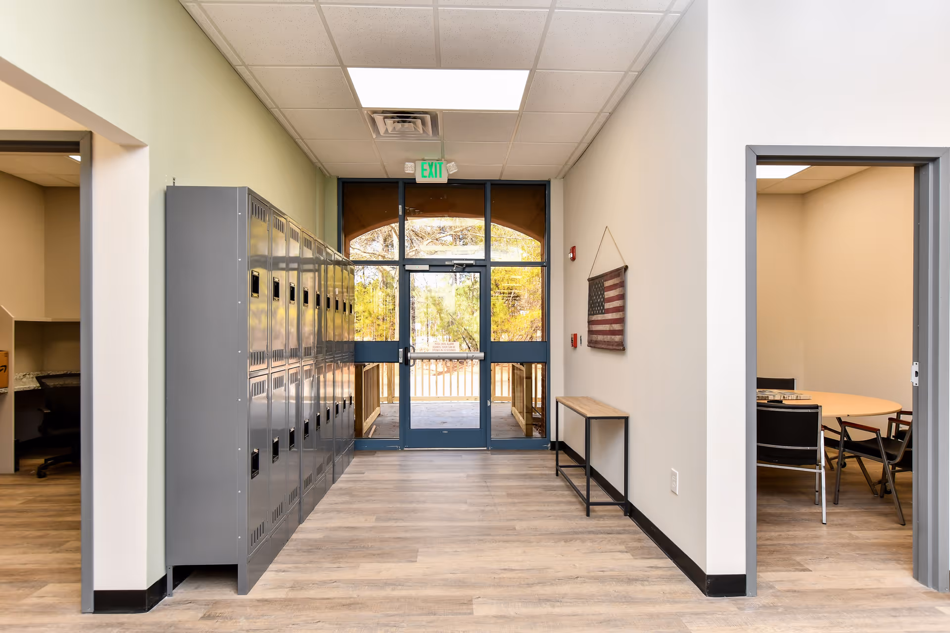 Interior hallway with lockers, glass double doors, and a small meeting room on the right.