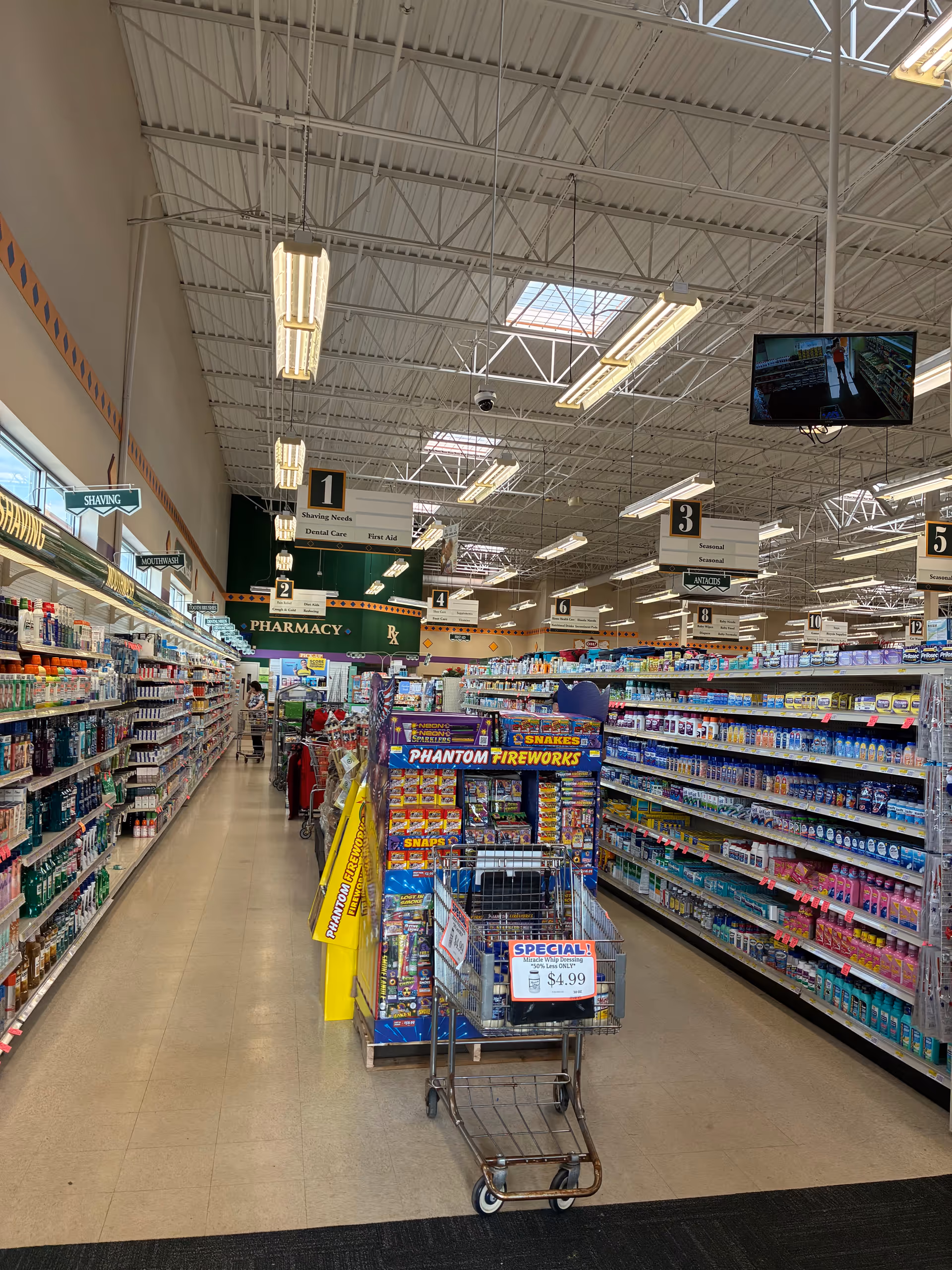Inside a Discount Drug Mart store, long aisles with shelves of products and a shopping cart.