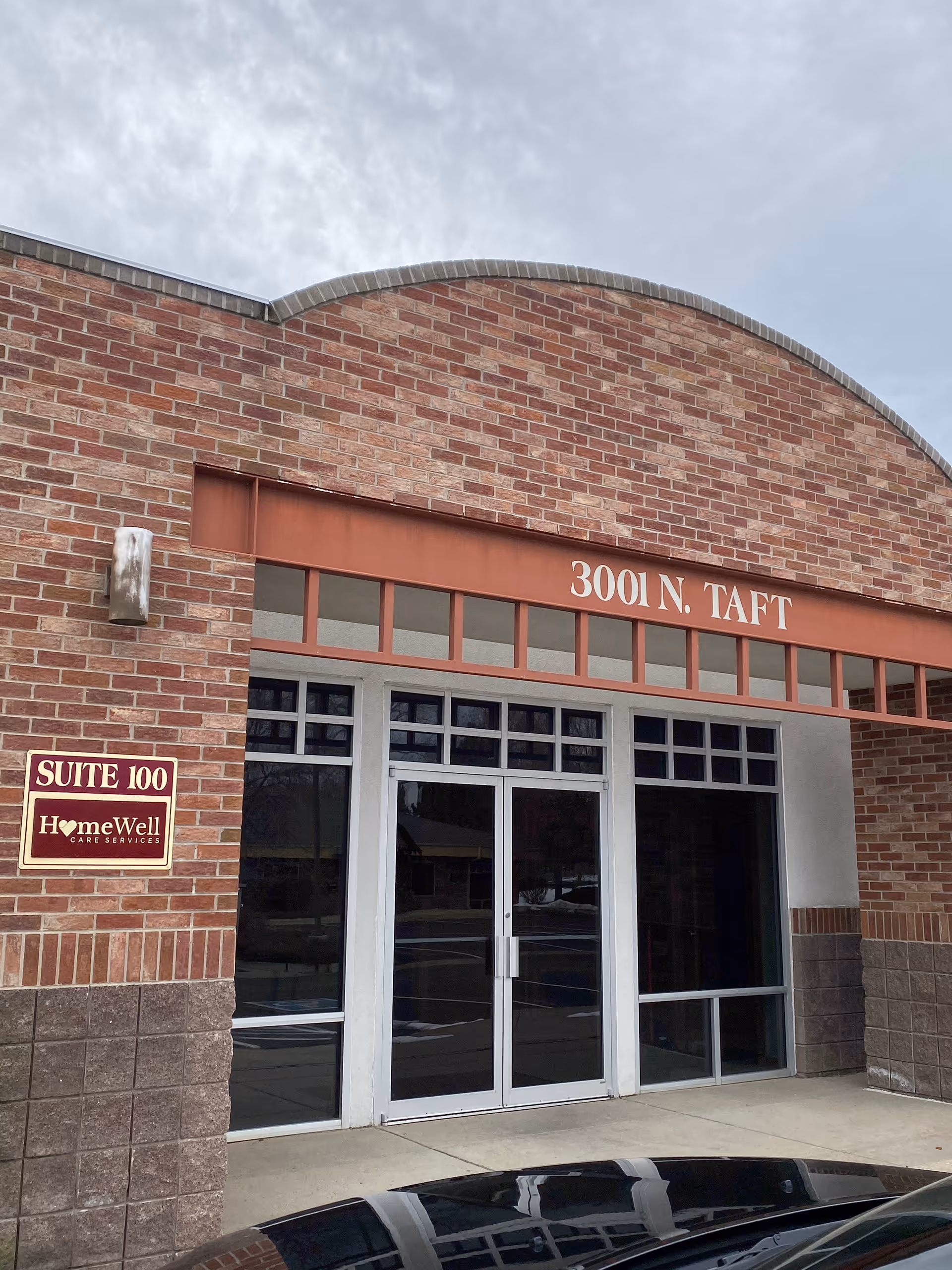 Brick storefront with glass double doors and a Suite 100 HomeWell sign.