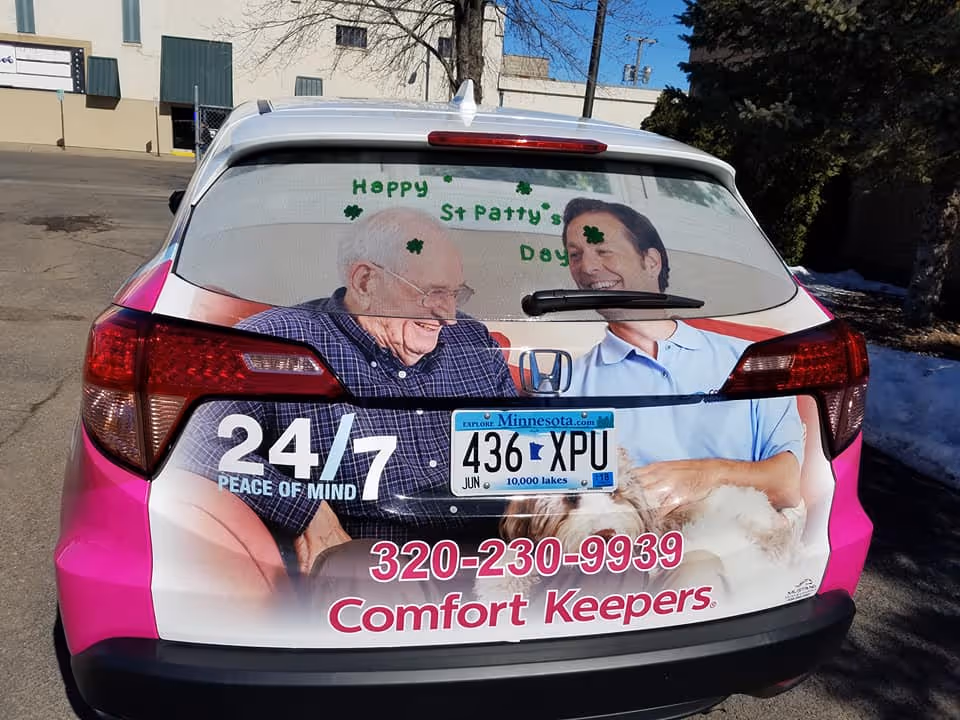 Back of pink Comfort Keepers promotional car with elderly care imagery.