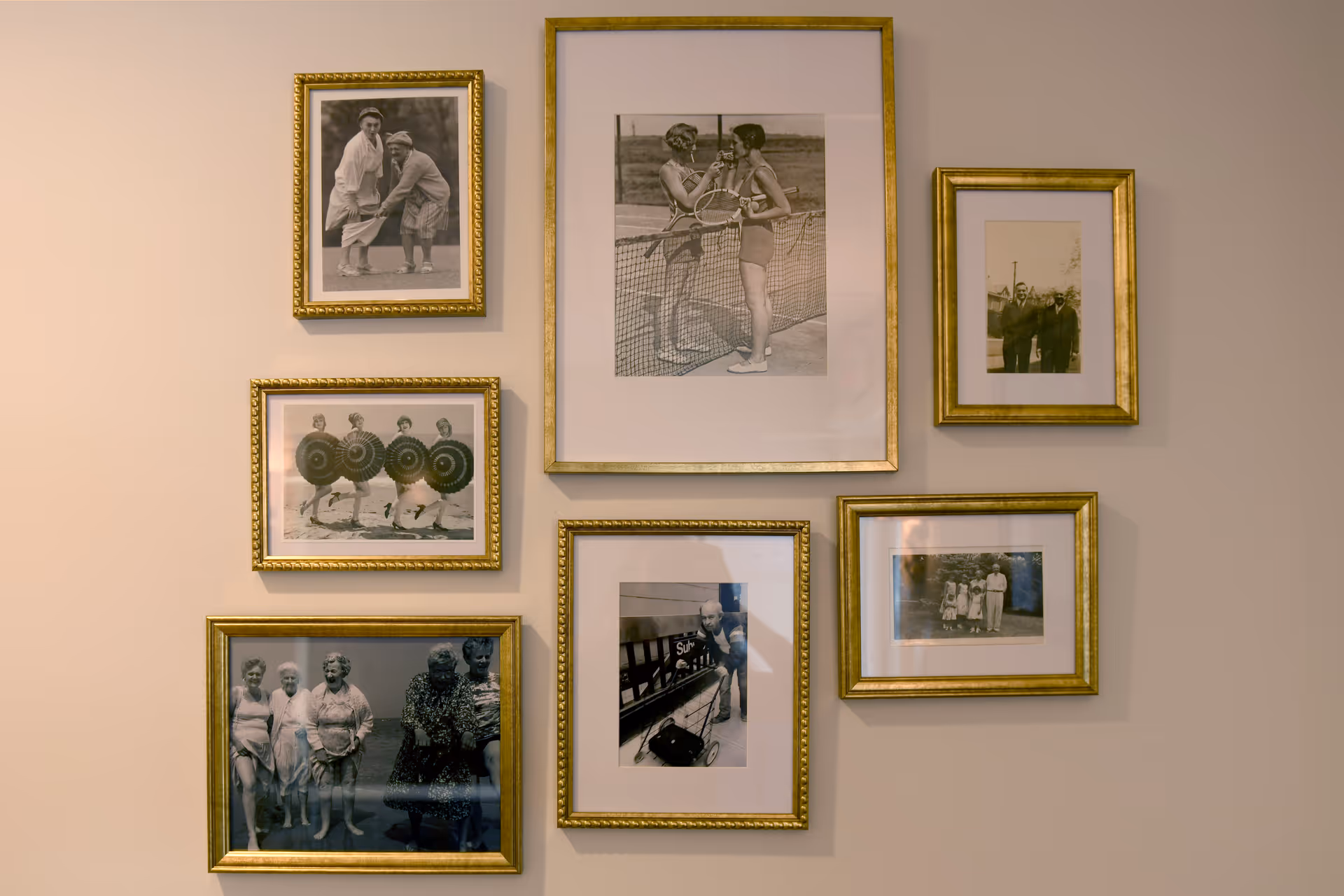 A gallery wall of gold-framed black-and-white photos arranged in a grid.