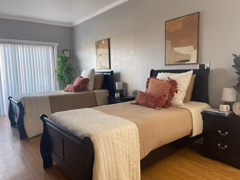 Two twin beds with nightstands and abstract wall art in a furnished bedroom.