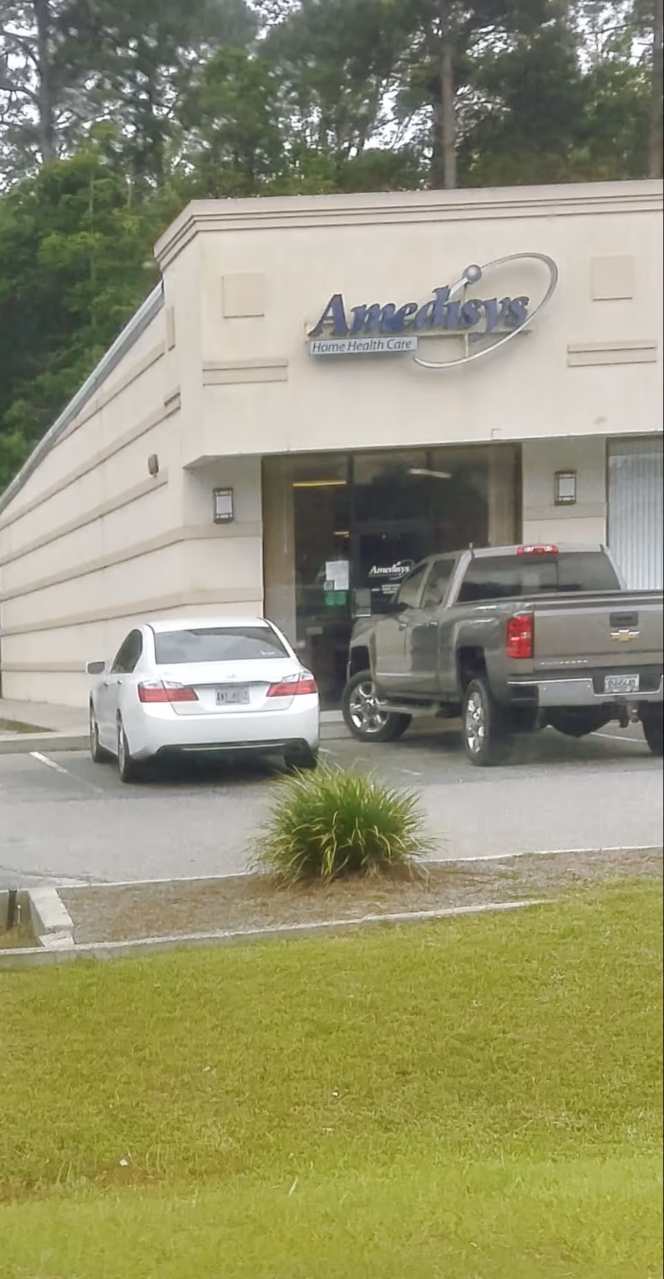 Exterior view of Amedisys Home Health Care building with parked cars.