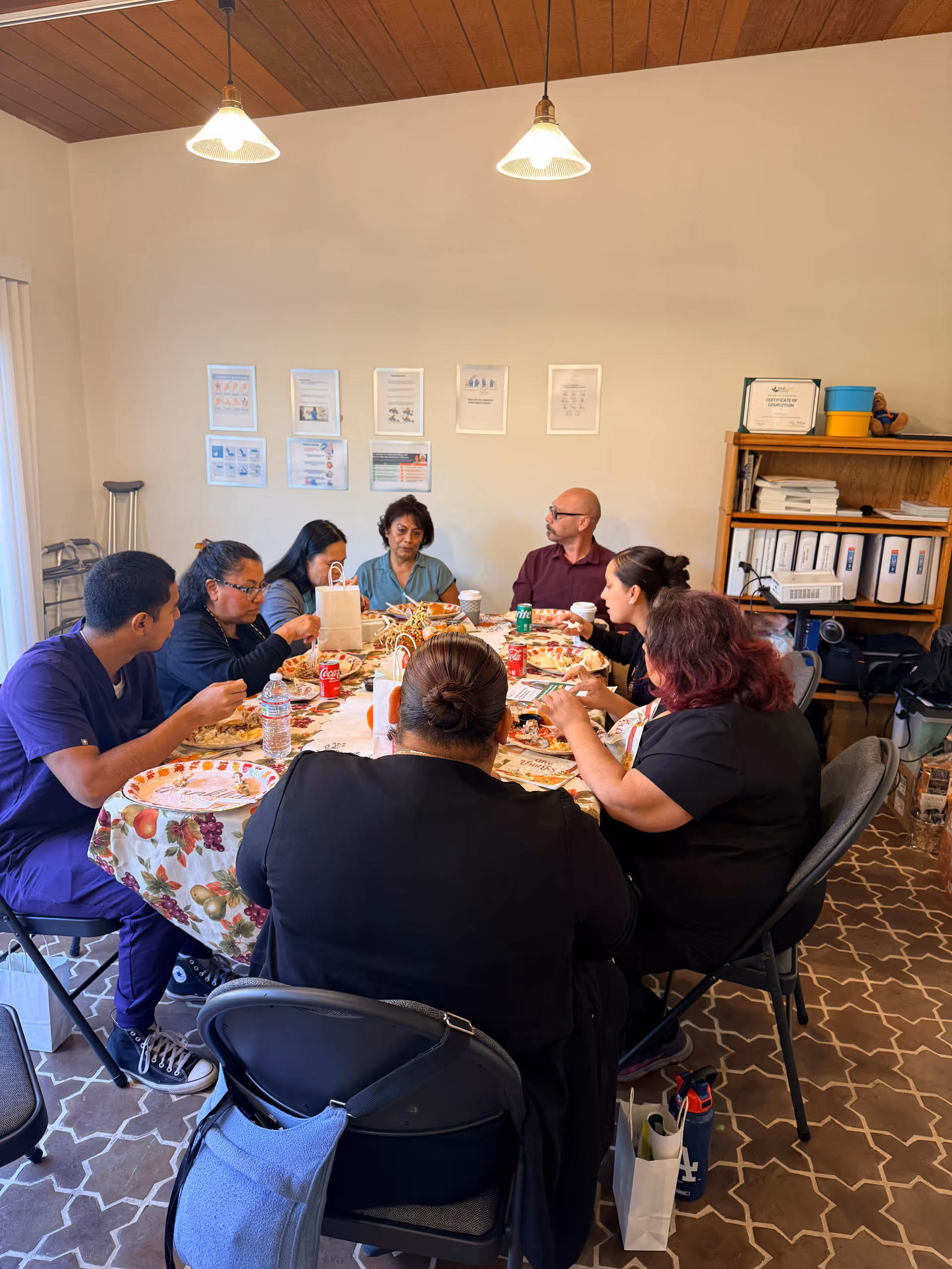Group of adults seated around a decorated table sharing a meal in a dining room.