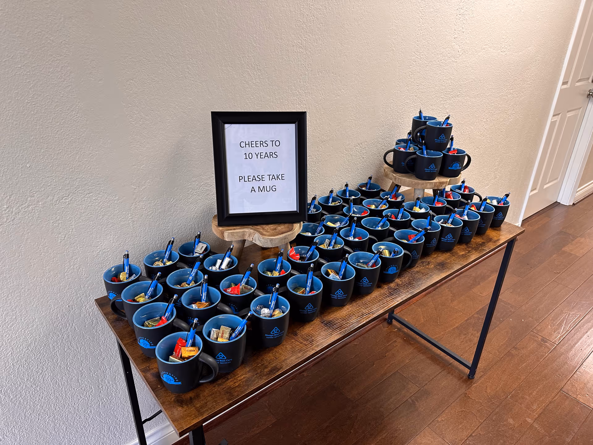 A long table with blue mugs, snacks, and a sign reading 'Cheers to 10 years'.