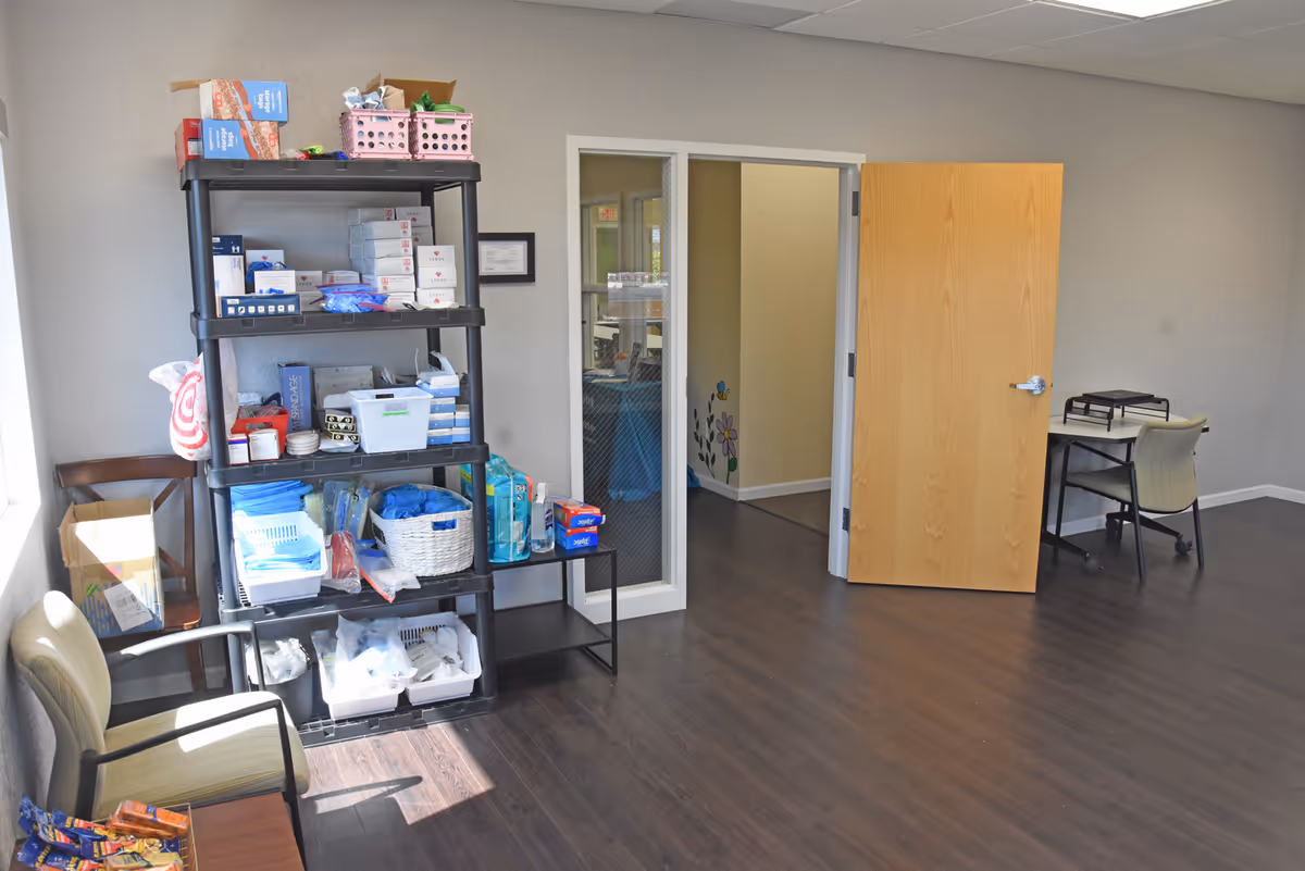 A storage room in a senior care facility with a tall shelf of supplies and doorway.