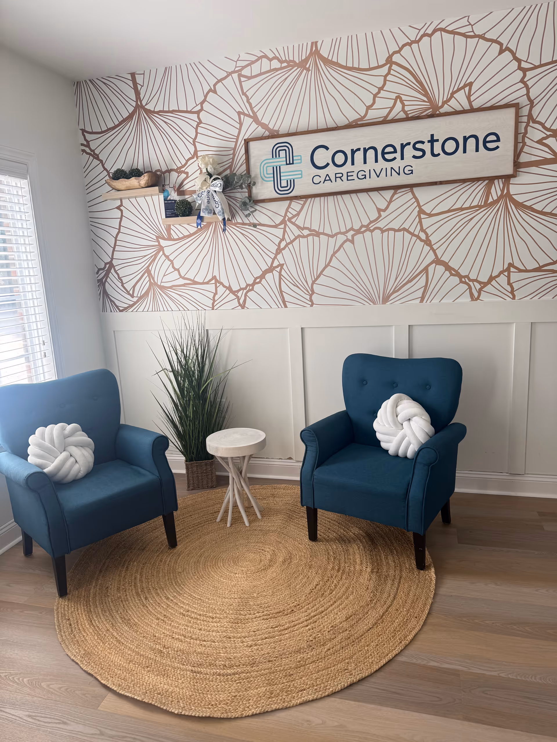 Two blue armchairs sit around a small white table in a decorated Cornerstone Caregiving waiting area.