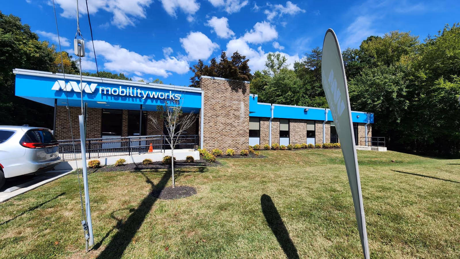 Exterior view of MobilityWorks facility with blue signage and parked white SUV.