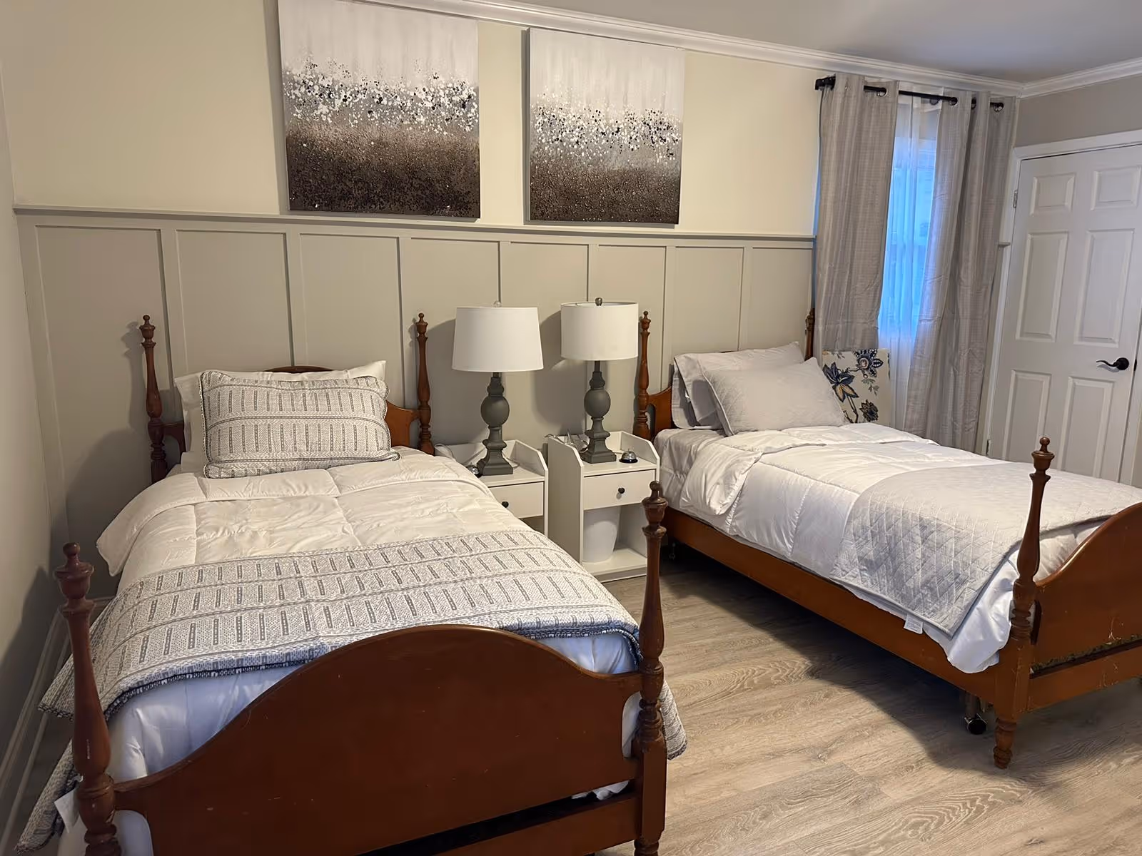 Two single beds with matching bedding and a nightstand in a beige-paneled bedroom.