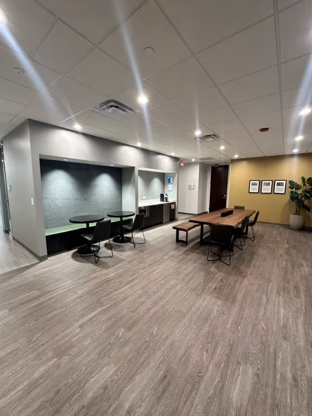 Bright, modern facility lobby with seating alcove, kitchenette, and long communal table.