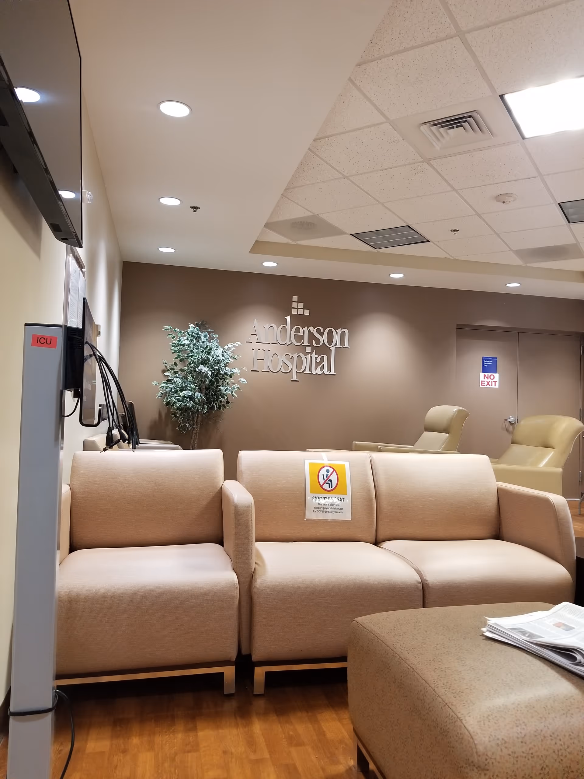 Interior hospital lobby with beige seating, a potted plant, and an Anderson Hospital sign.