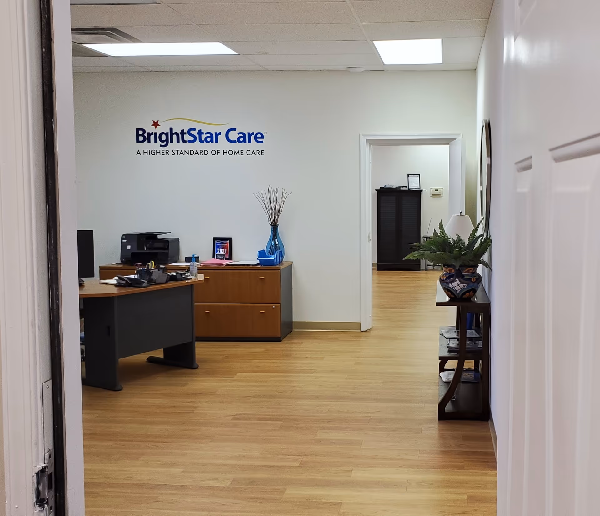 BrightStar Care reception area with desk, logo on wall, plants, and a hallway.