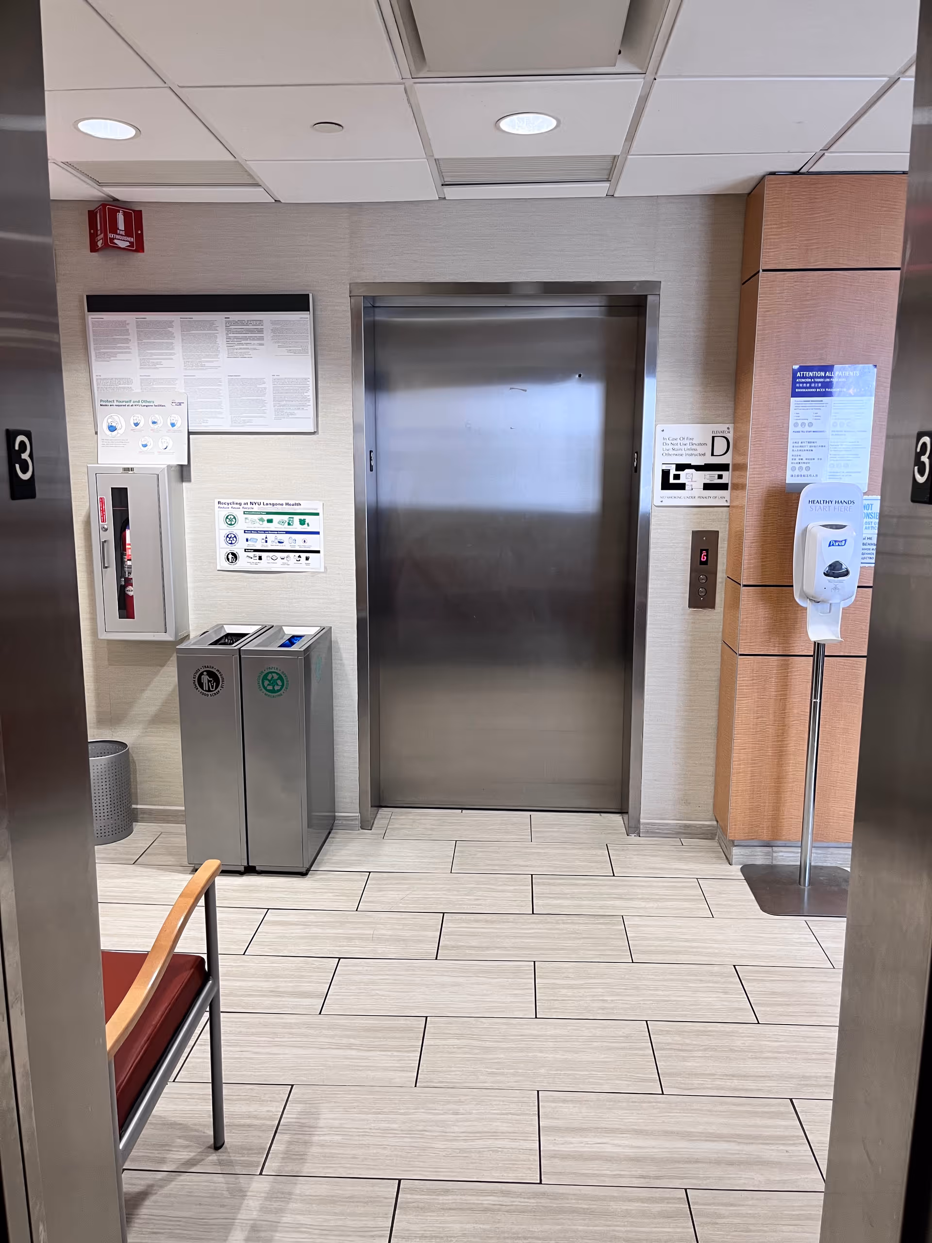 Interior hallway with elevator doors, a trash bin, and sanitizer station.