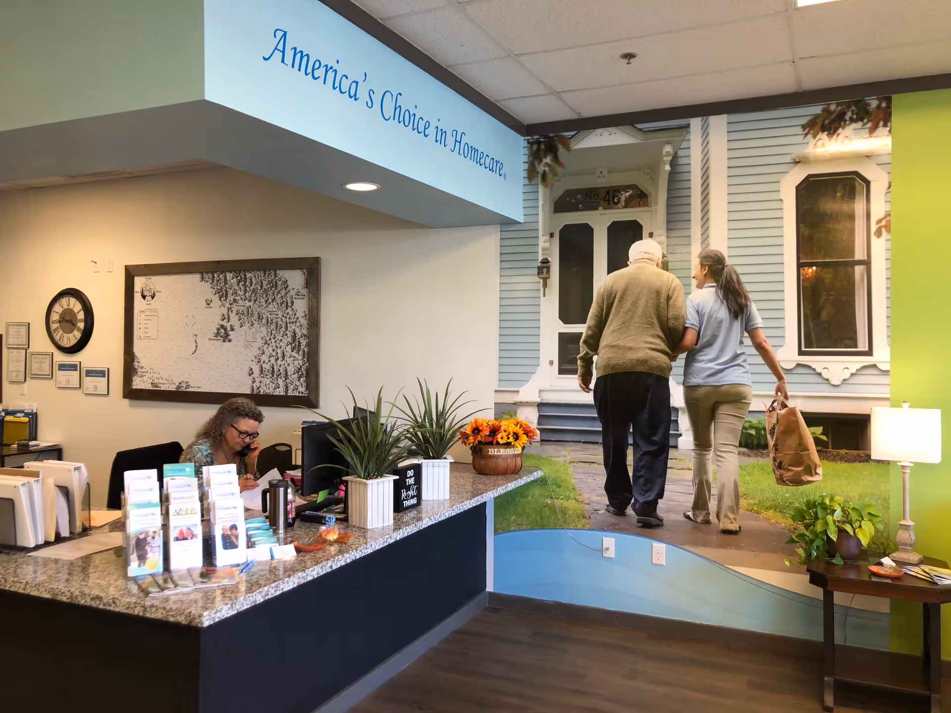 Lobby reception desk with brochures; a mural of two people walking to a blue house.