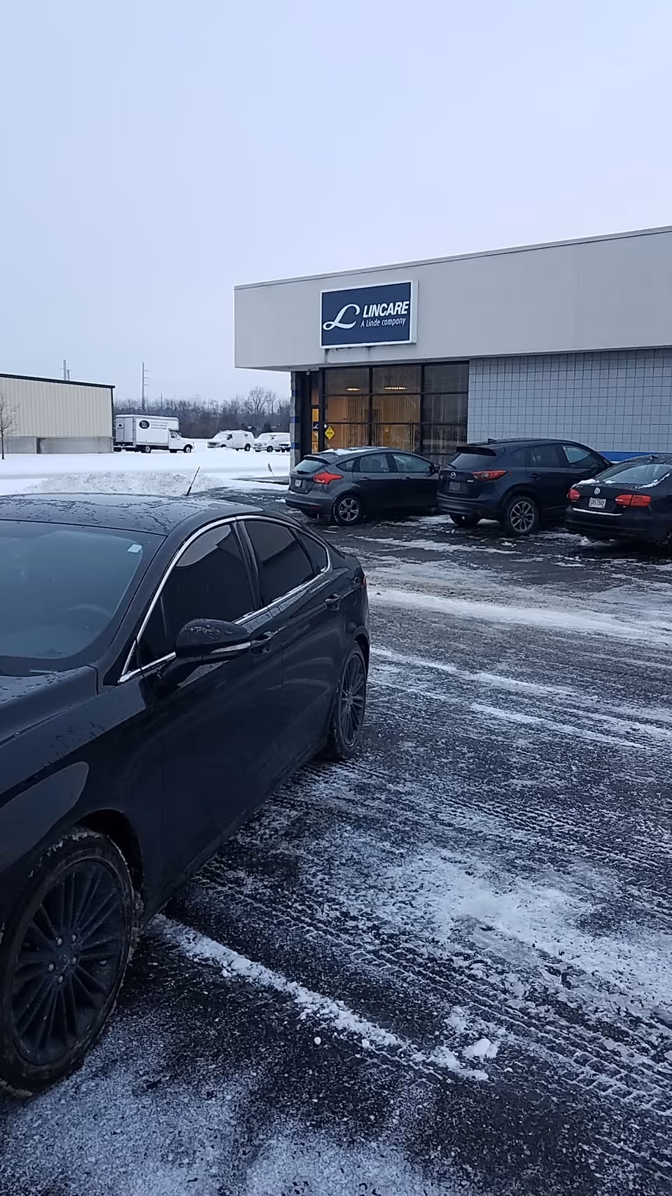 Front exterior of LINCARE INC. facility with parked cars in a snowy lot.