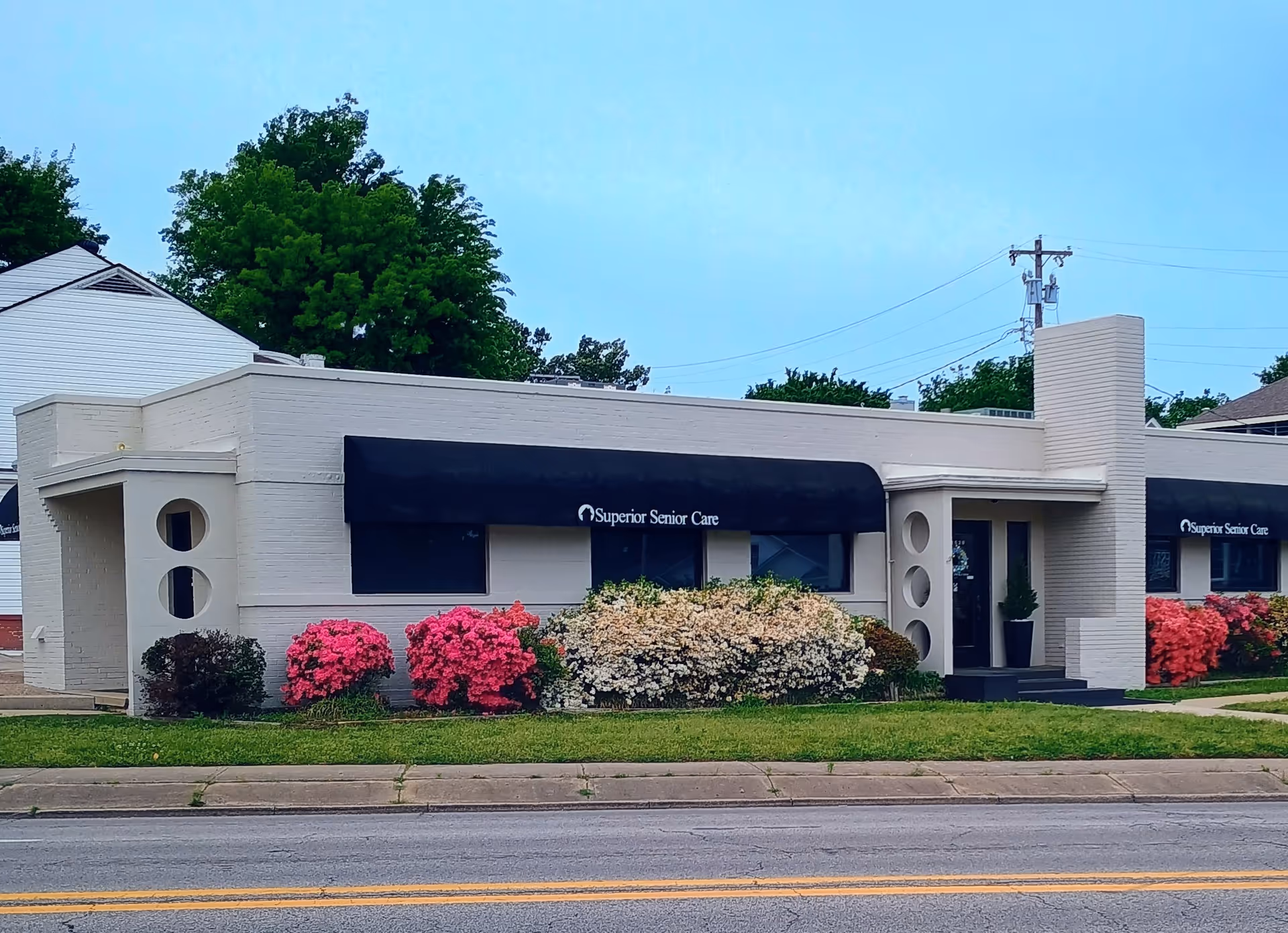 Exterior view of Superior Senior Care facility with blue awnings and flowering shrubs