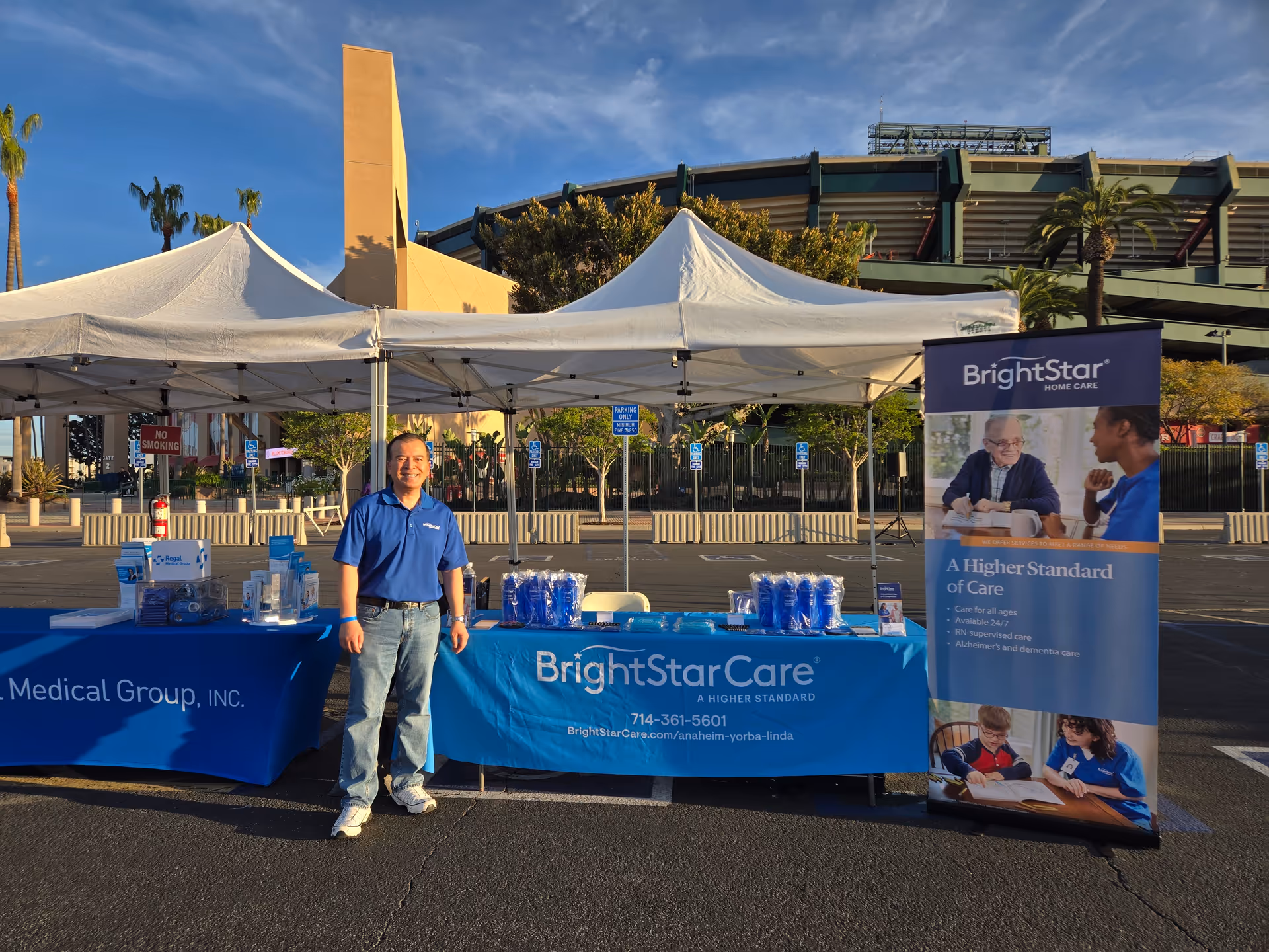 BrightStar Care promotional outdoor booth with a man in a blue shirt beside banners.