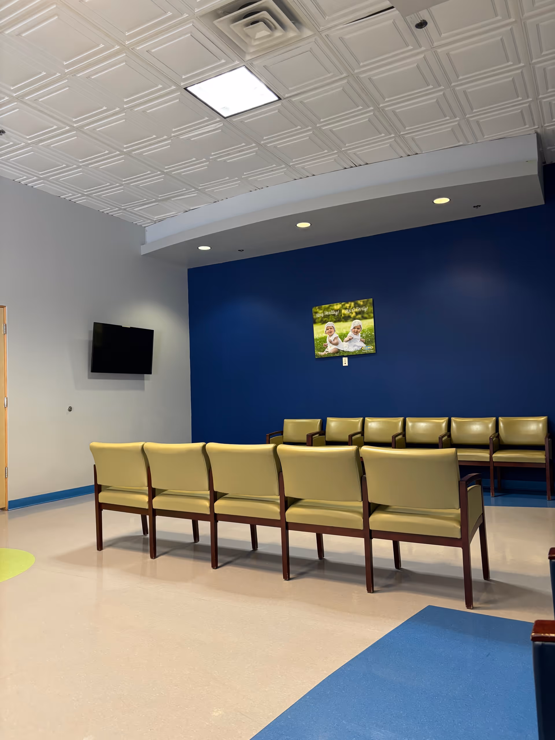 Waiting area with lime-green chairs, blue wall, and a wall-mounted TV.