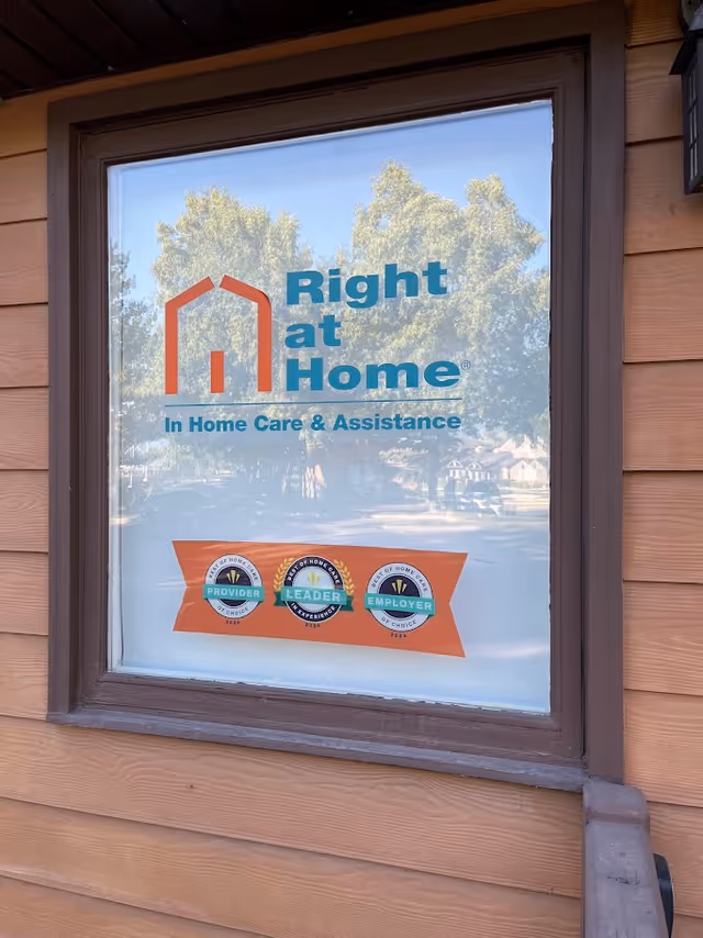 Window on a wood exterior displays the Right at Home logo and slogan.