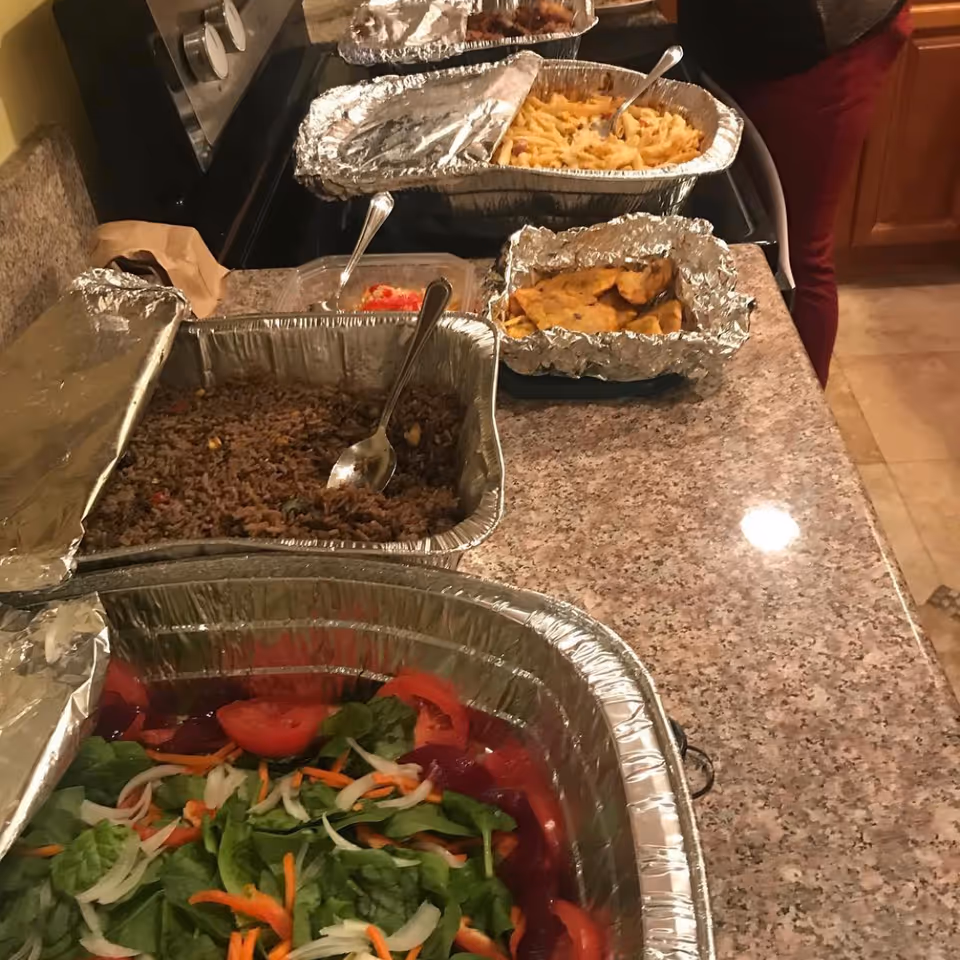 Foil-covered food trays lined up on a kitchen counter in a senior living facility