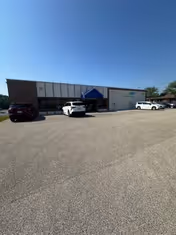 Exterior view of MobilityWorks storefront with a blue tent canopy and parked cars in the lot.