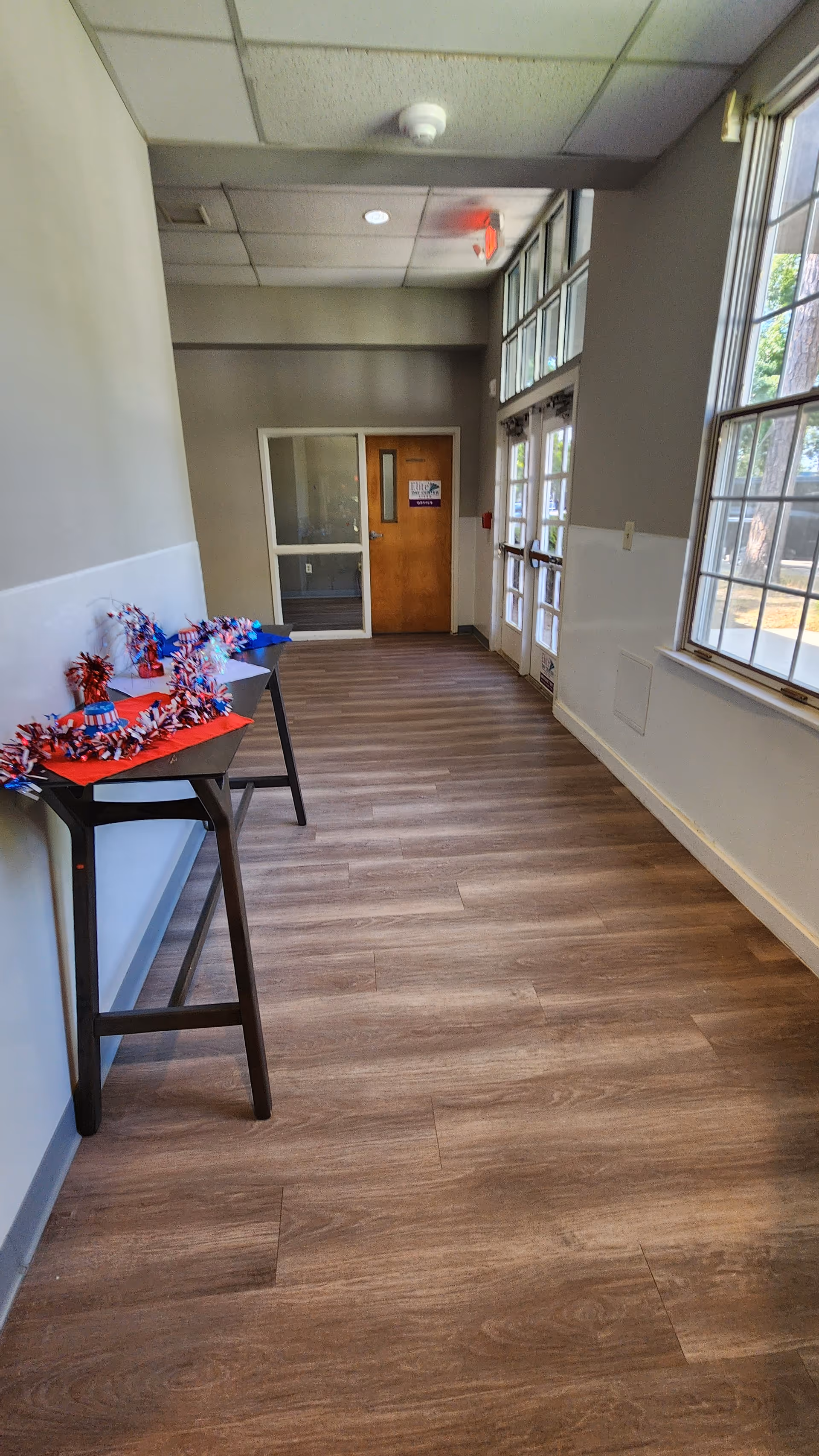 Long, well-lit interior hallway inside Elite Home Care, with patriotic decorations on side tables.