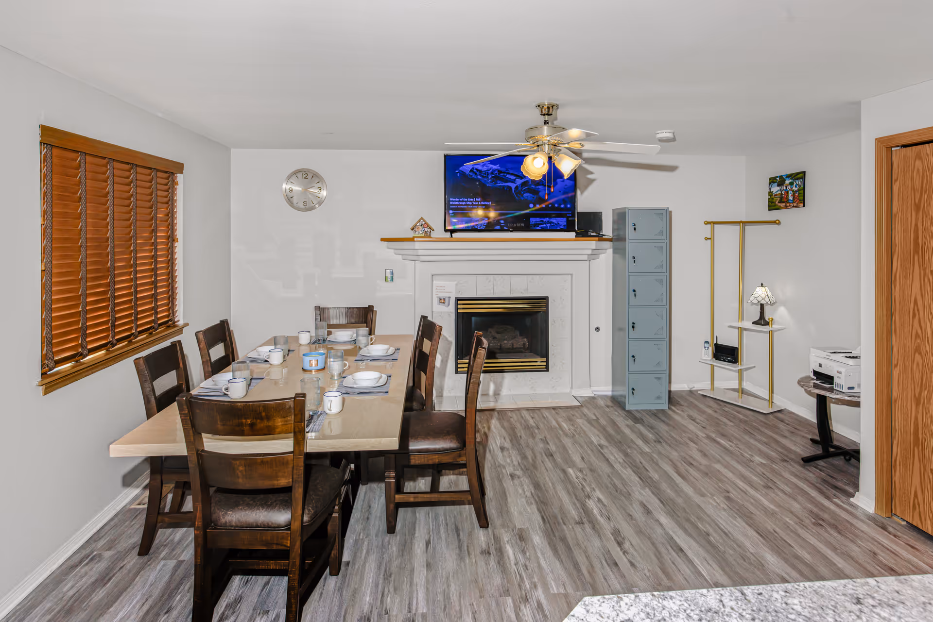 Dining room with a long table set for meals, fireplace, TV, and storage cabinet.