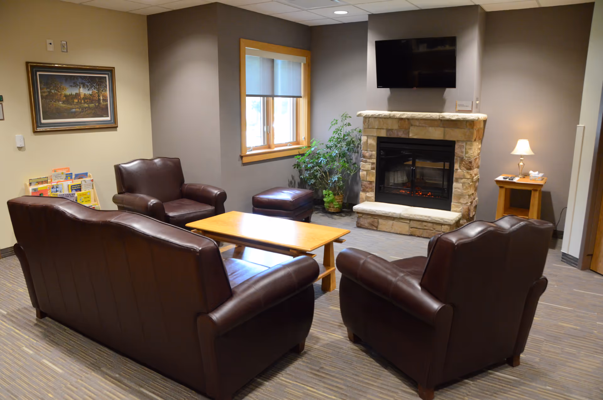 A cozy living room with leather chairs, a coffee table, and a stone fireplace.