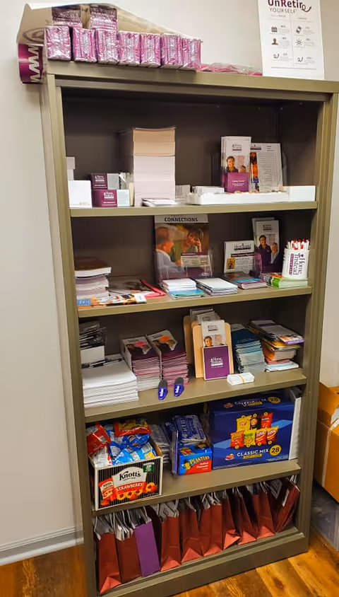 A tall beige information shelf filled with pamphlets, brochures, and packets in a facility.