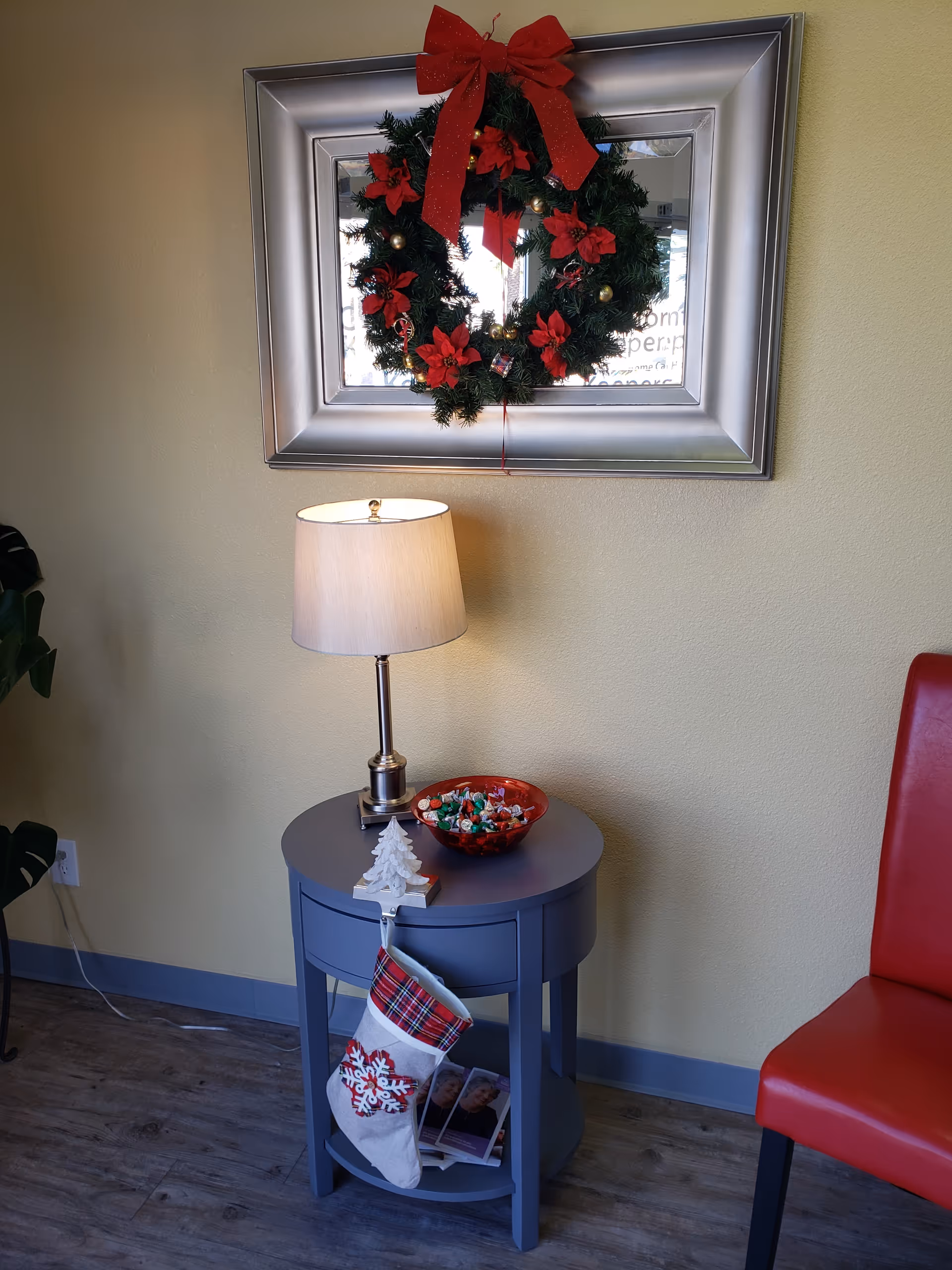 Blue round side table with lamp, candy bowl, stockings, wreath, indoors.