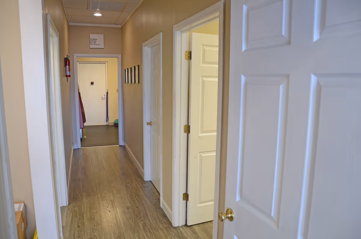 Interior hallway with beige walls, white doors, and wood-like flooring.