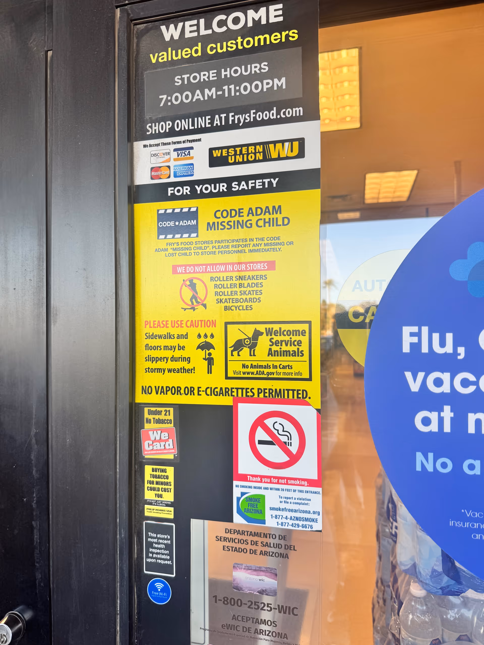 Storefront door covered with safety posters and promotional signs at Fry's Pharmacy.