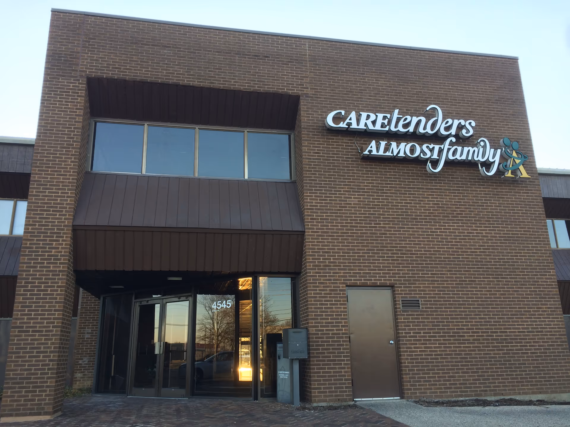 Exterior brick front of Caretenders Almost Family building with glass entrance