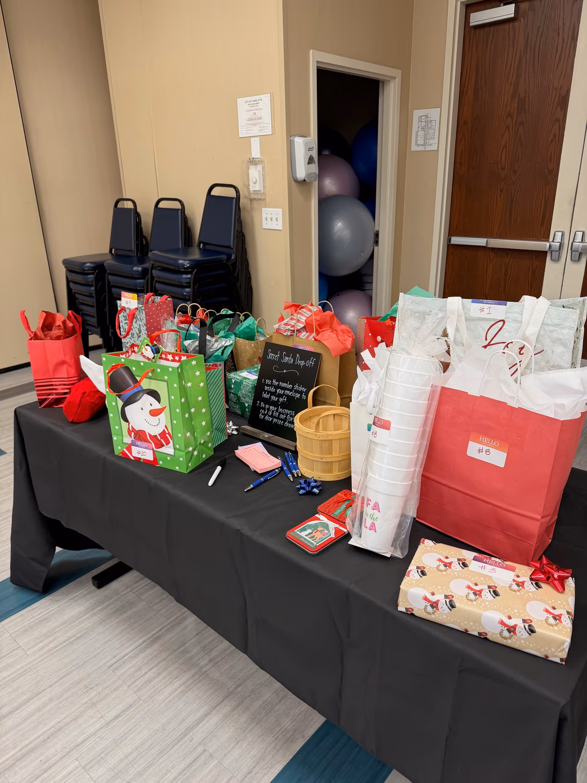 Table with gift bags, wrapped presents, and a Santa-themed setup in a senior living facility.