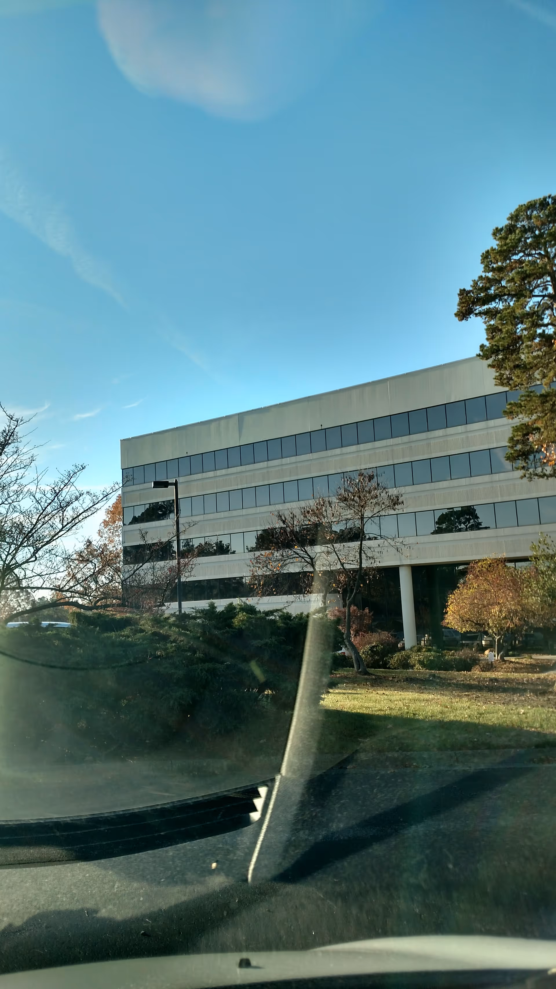 Exterior of a modern, glass-windowed building with landscaping and blue sky.