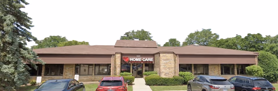 Exterior of a single-story building with Home Care sign and cars parked in front.