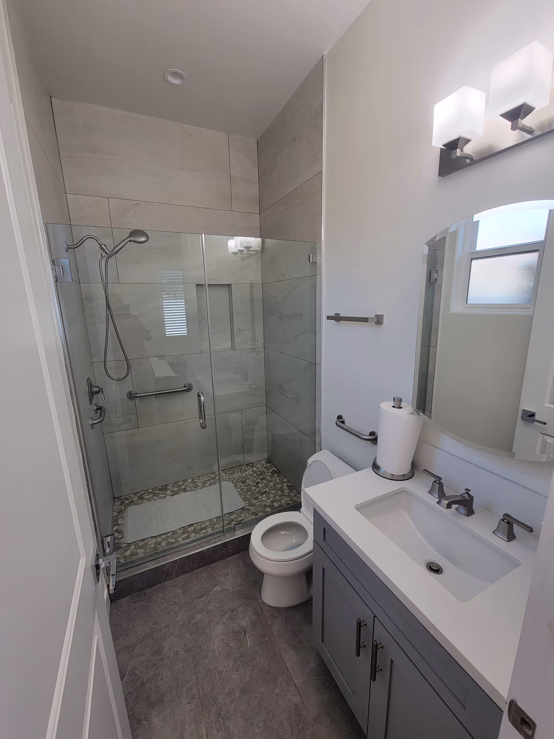 Modern bathroom with glass shower, toilet, and vanity