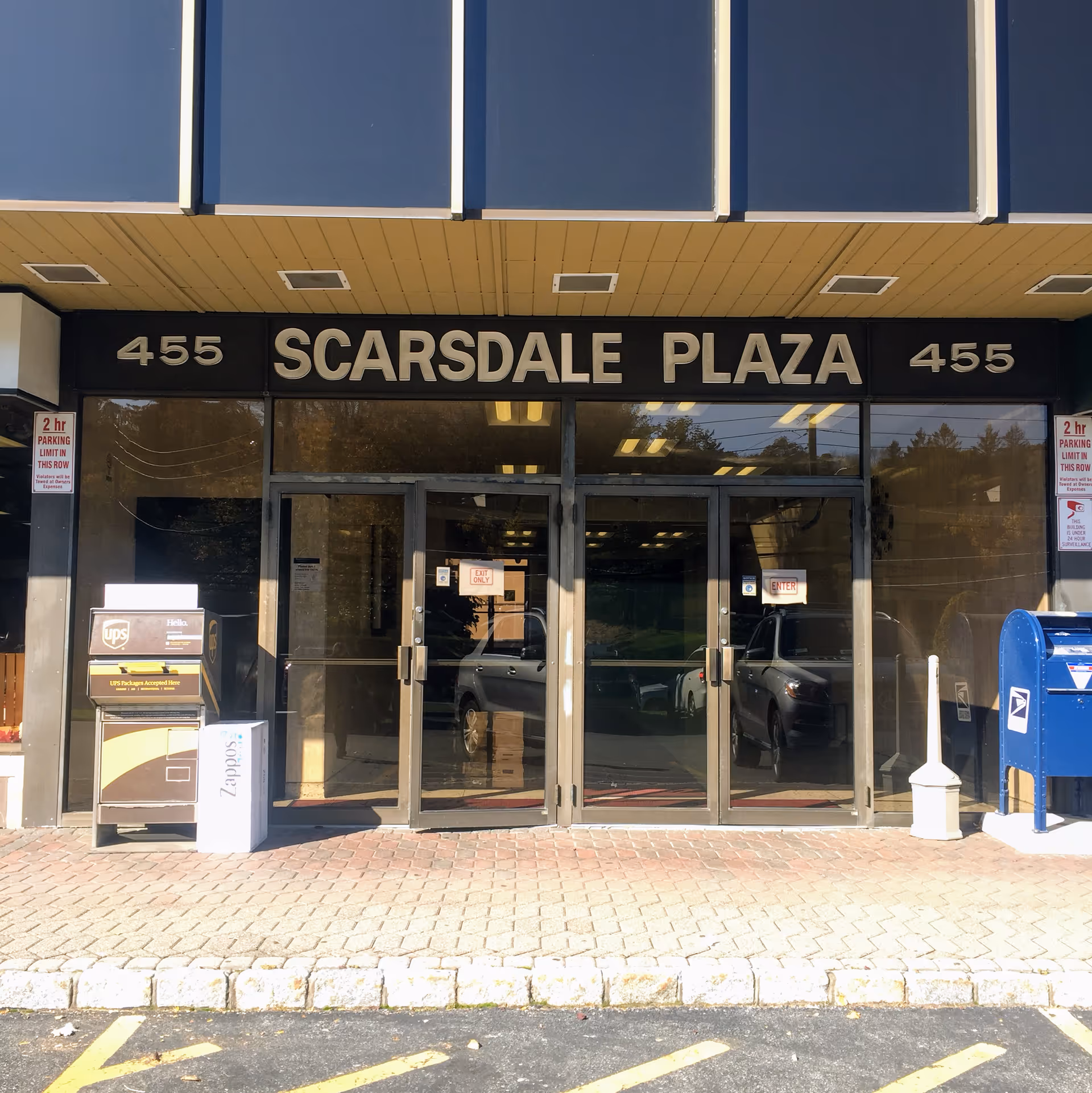 Front entrance of Scarsdale Plaza with glass doors and signage