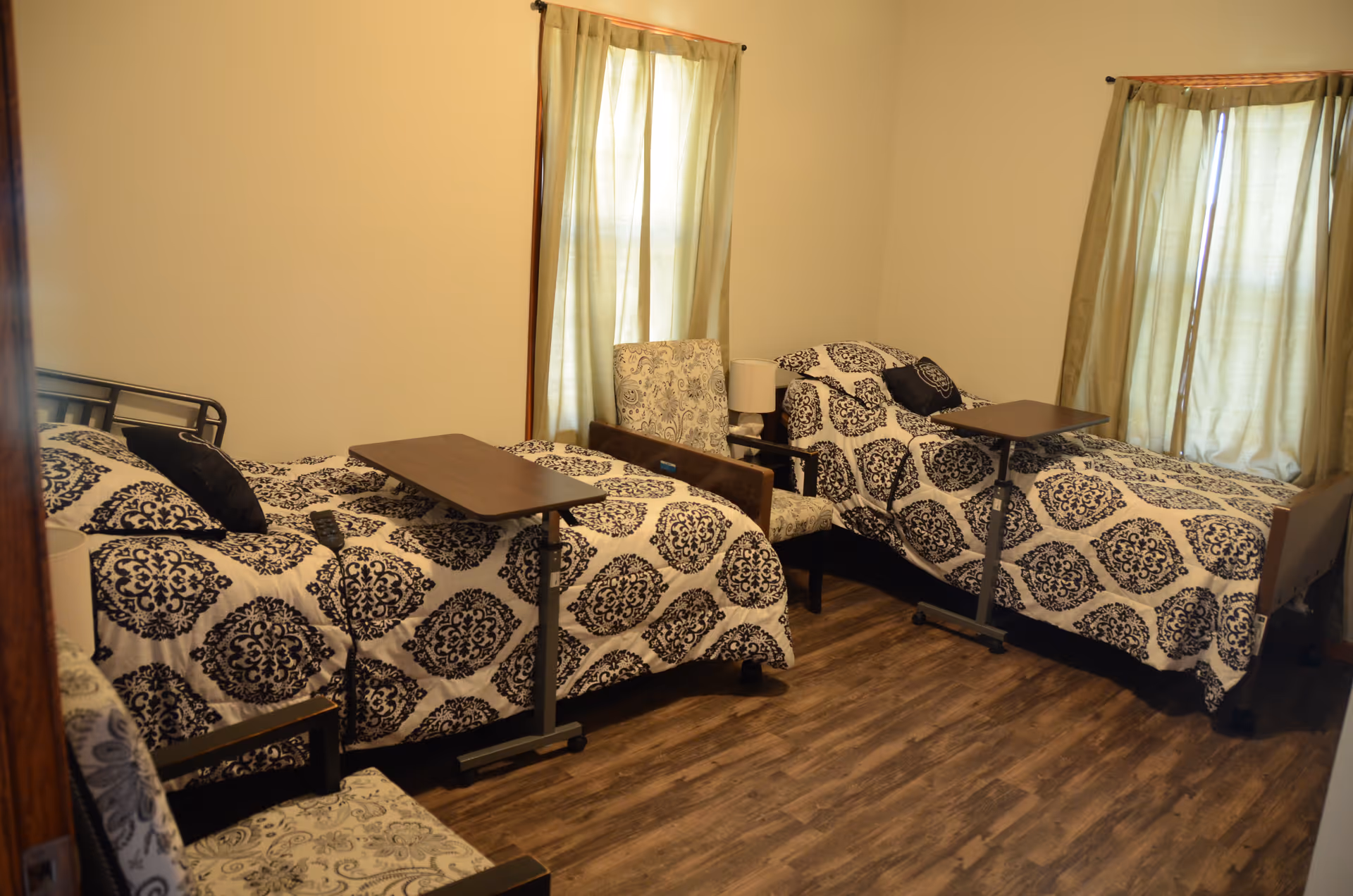 A shared bedroom with two twin beds, matching bedding, and overbed tables.