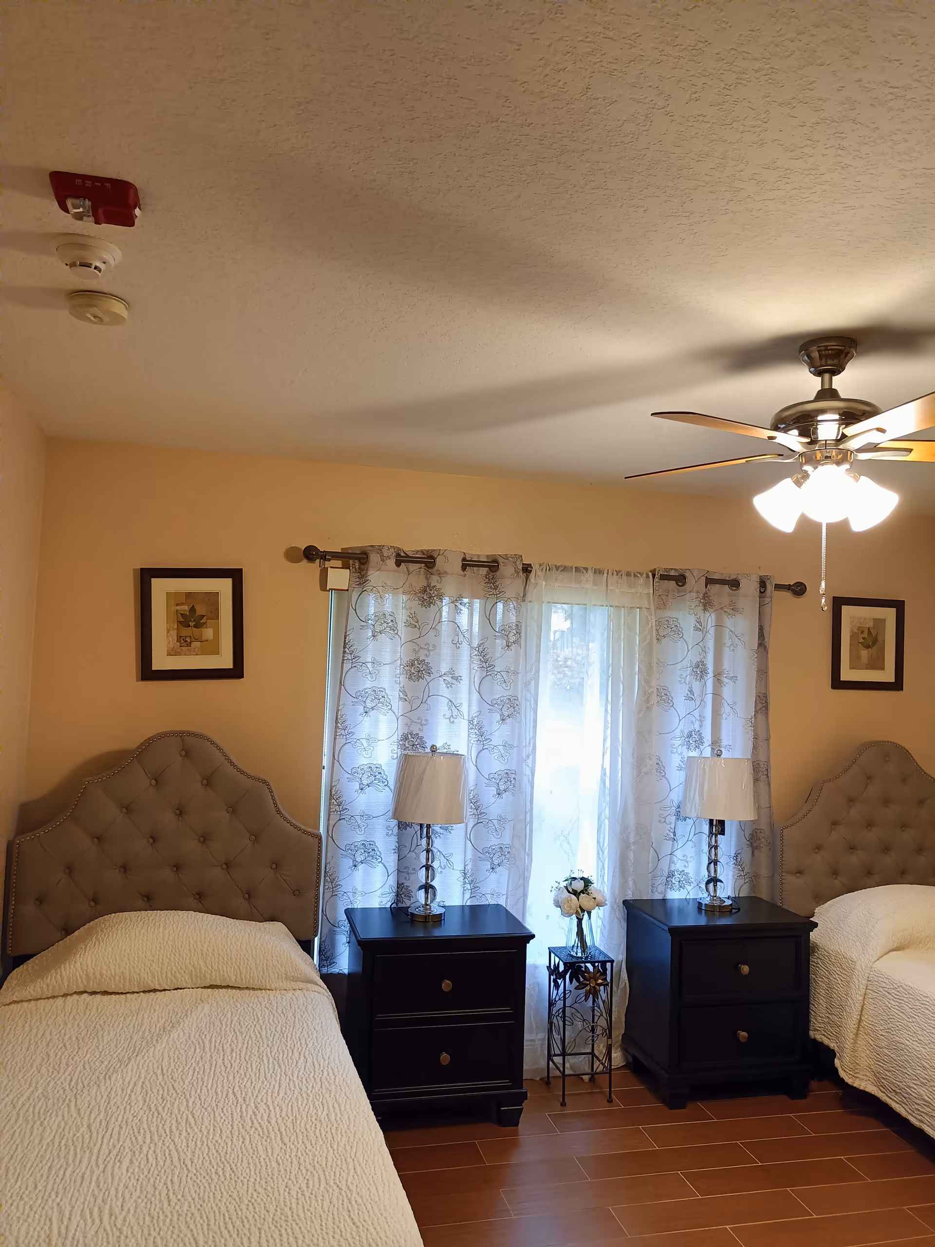 Two twin beds with tufted headboards flank matching nightstands and lamps in a cozy bedroom.