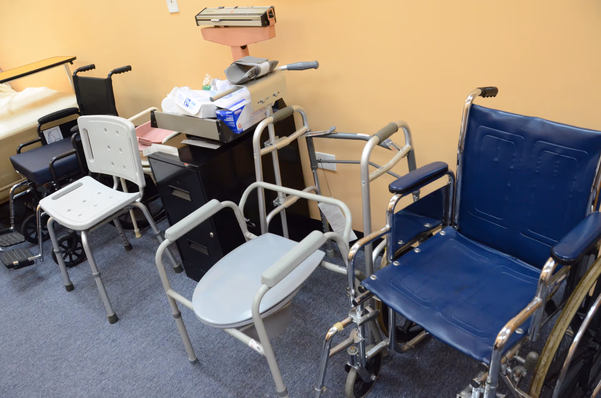 Medical equipment and chairs clutter a small interior room in a facility.